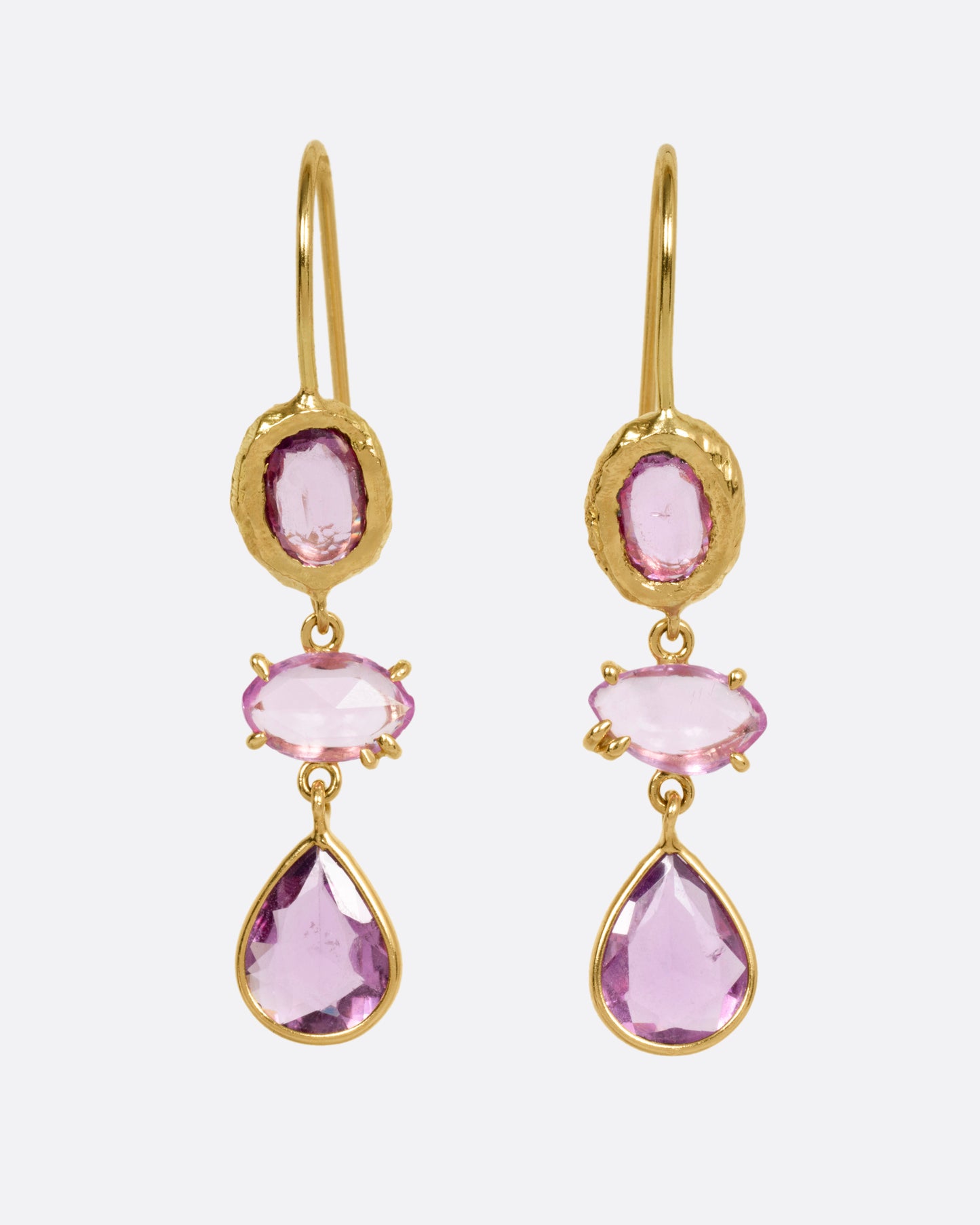 A pair of yellow gold earrings, each with three pink sapphires, shown from the front.