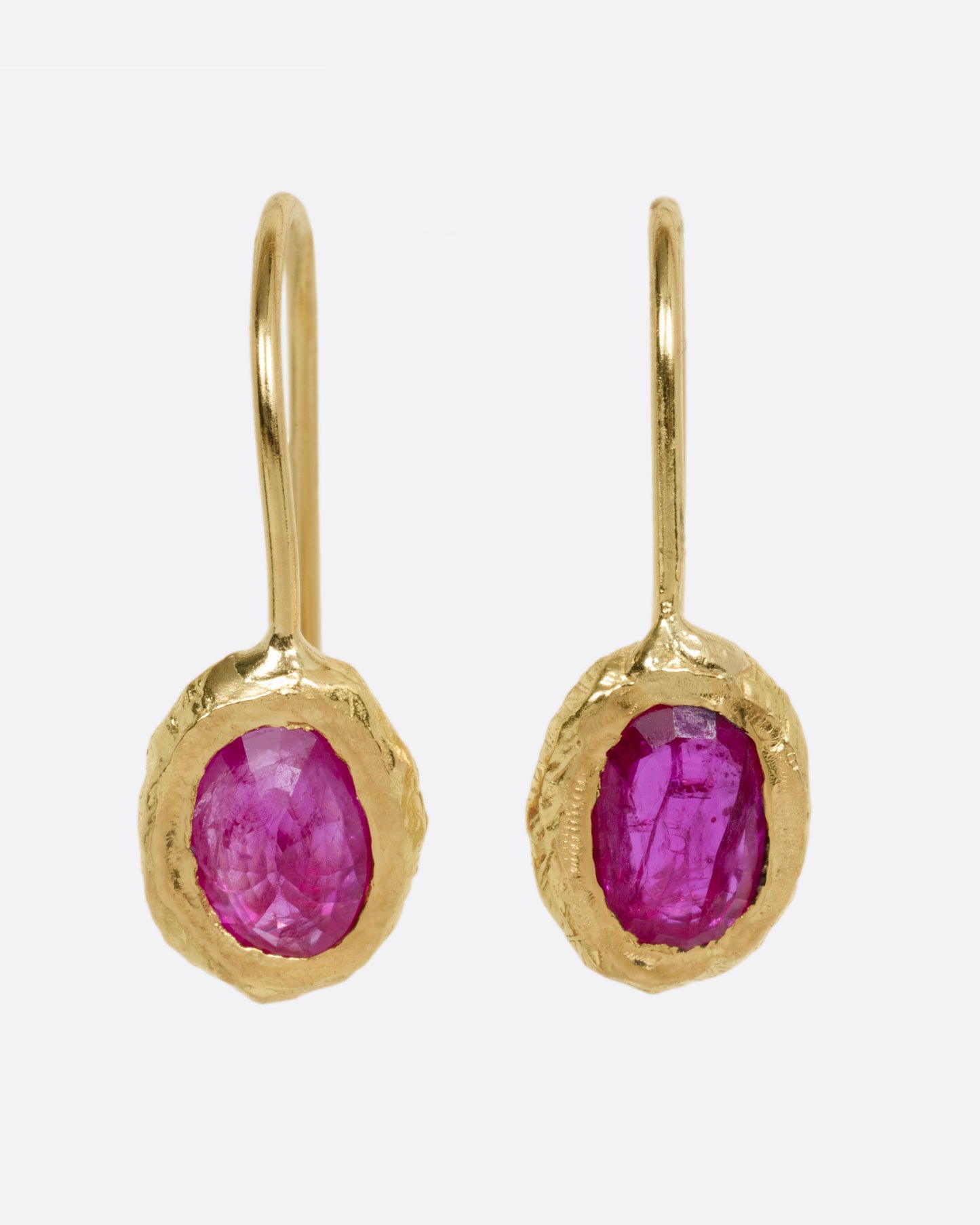 A pair of yellow gold earrings with rubies, shown from the front.
