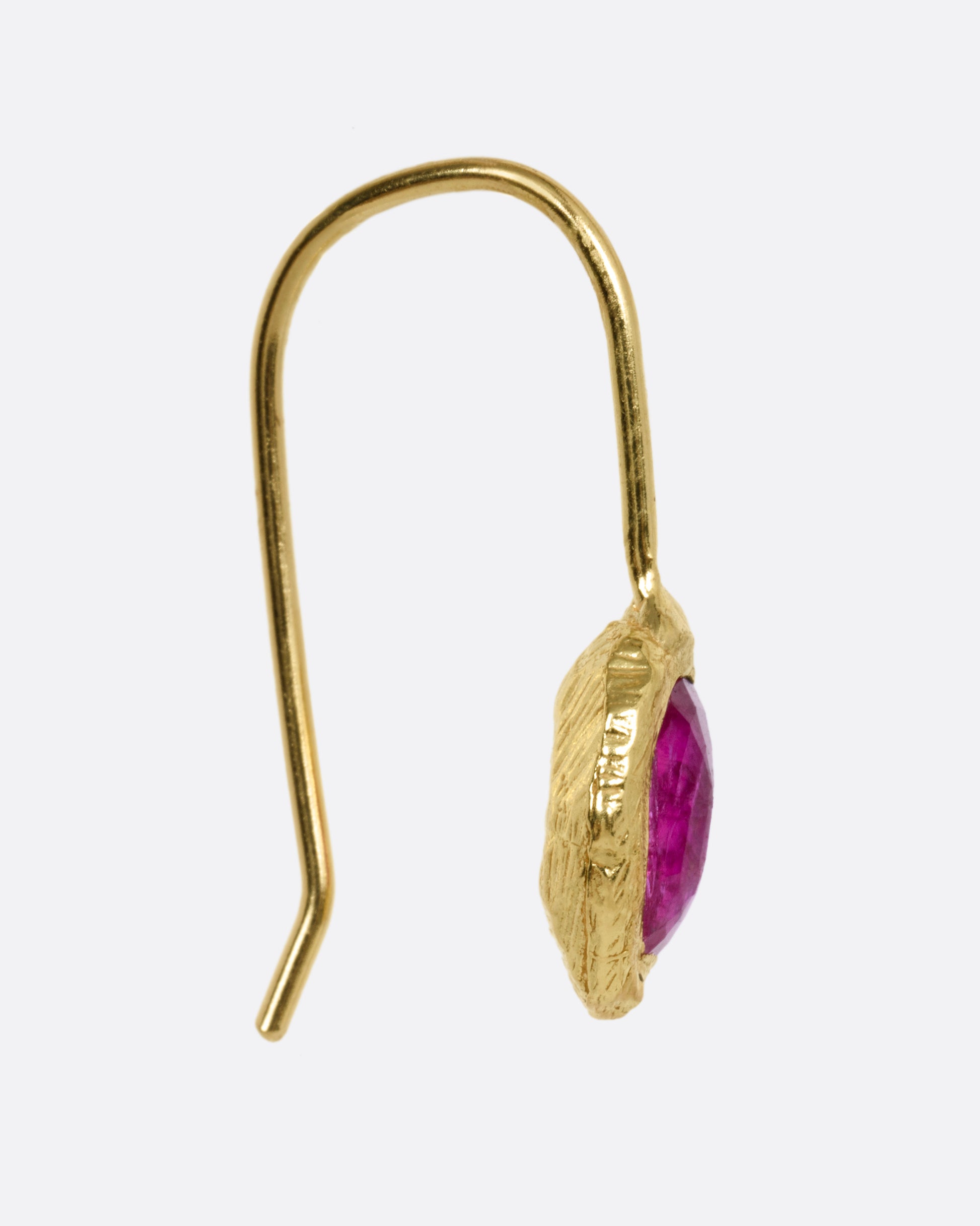 A yellow gold earring with a ruby, shown from the side.