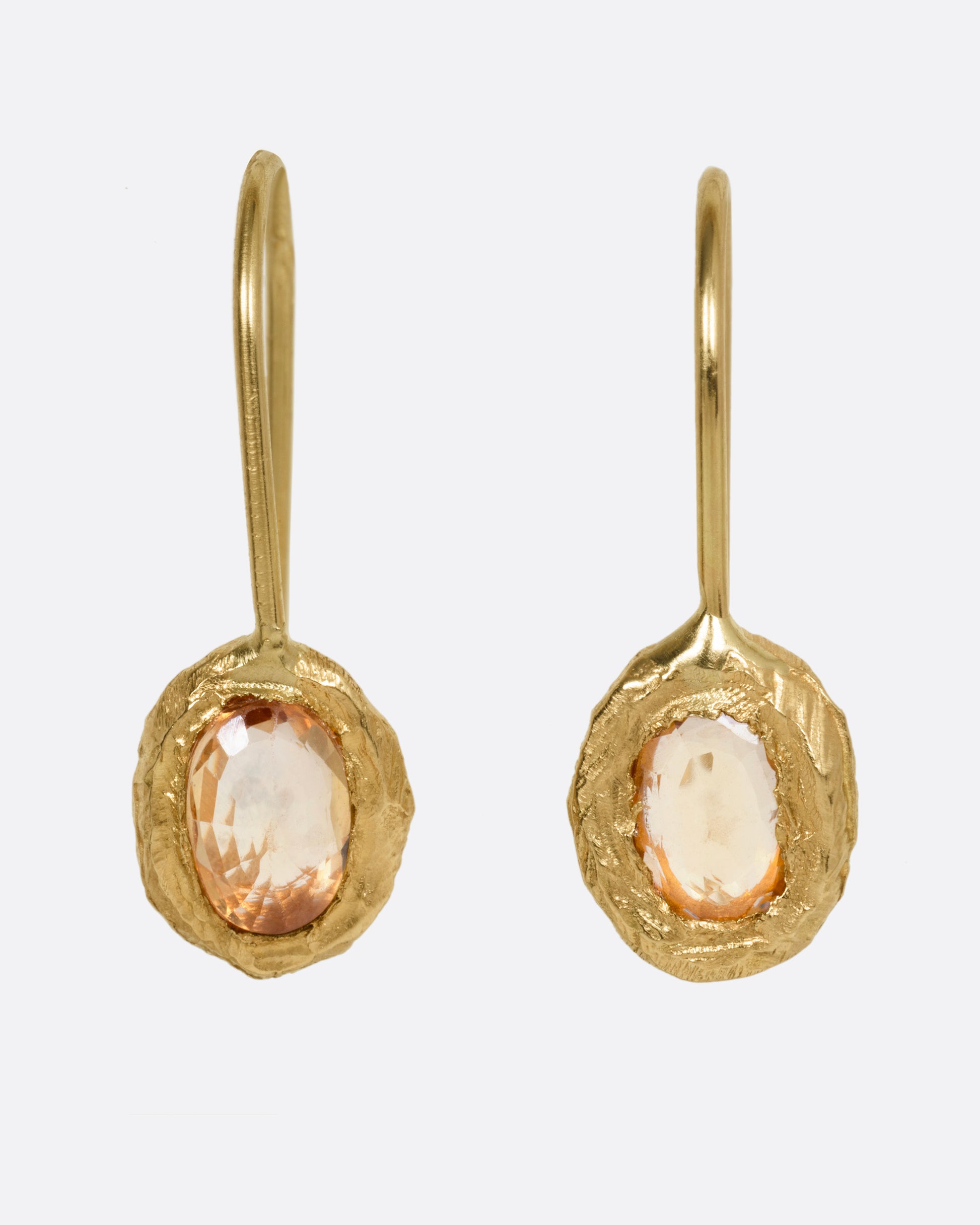 A pair of yellow gold earrings with yellow sapphires, shown from the front.
