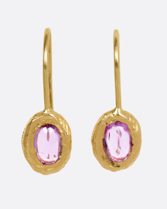 A pair of yellow gold earrings with pink sapphires, shown from the front.