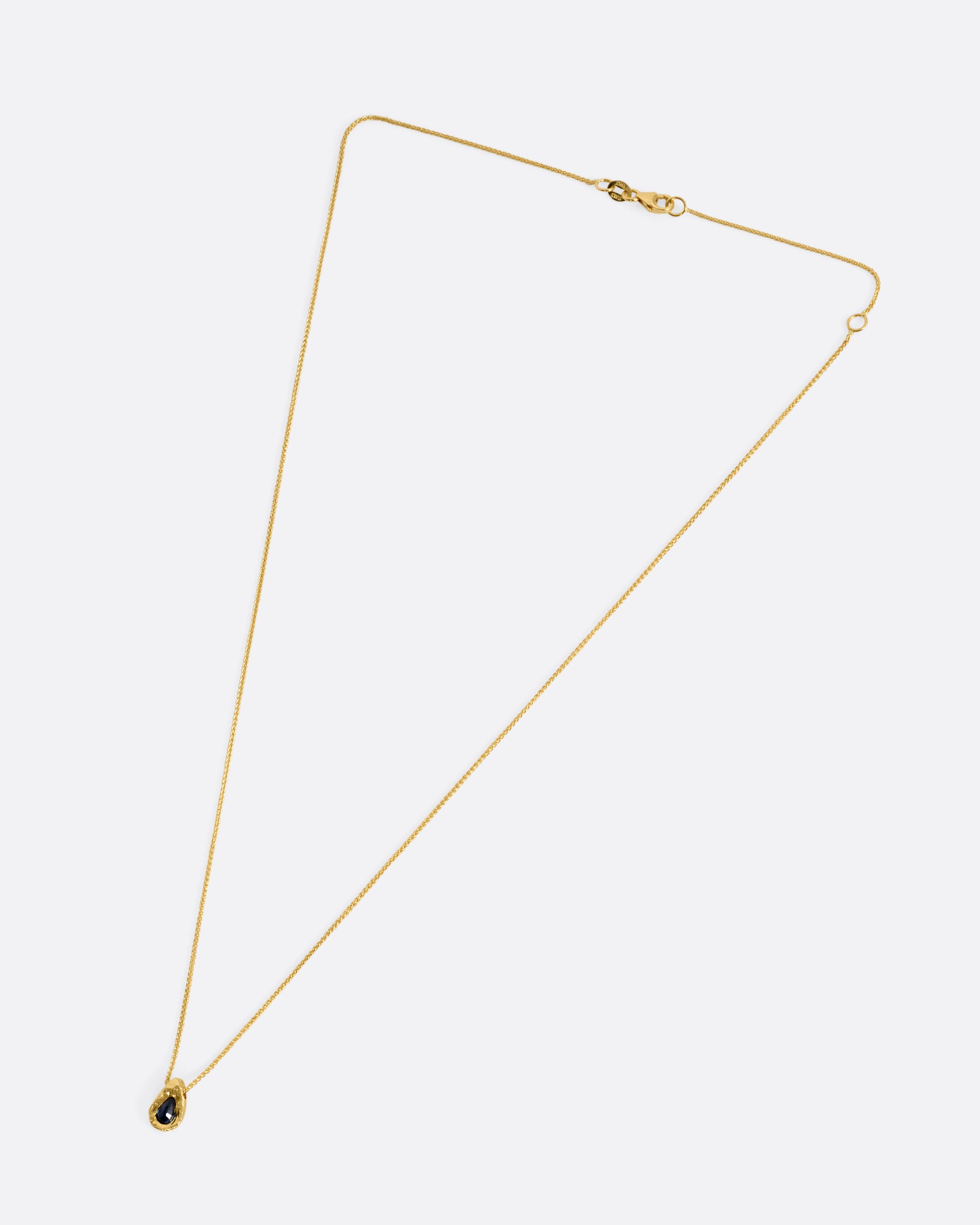 A yellow gold necklace with a blue sapphire pendant shown from the front.