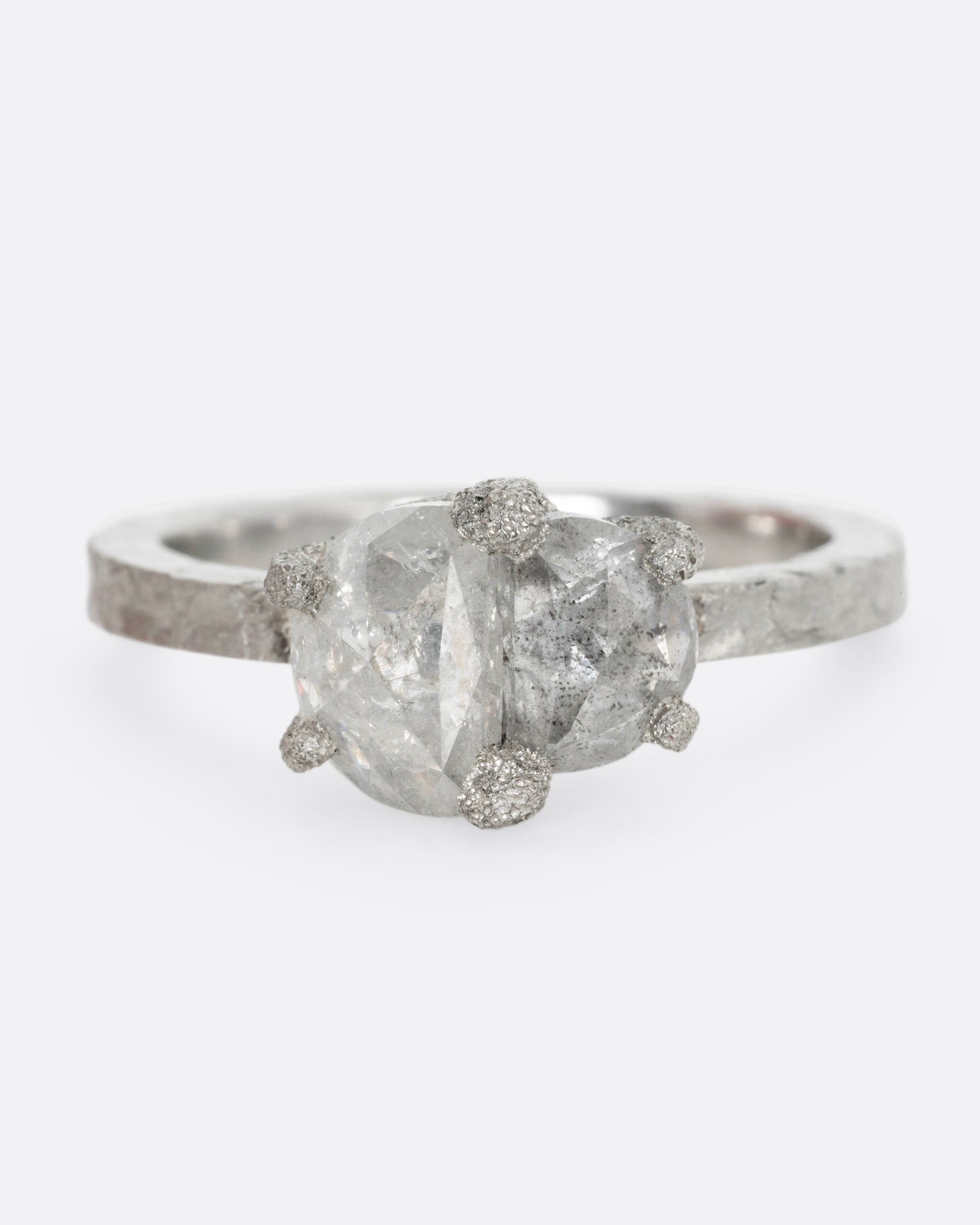 A platinum ring with two prong set rose cut diamonds, shown from the front.