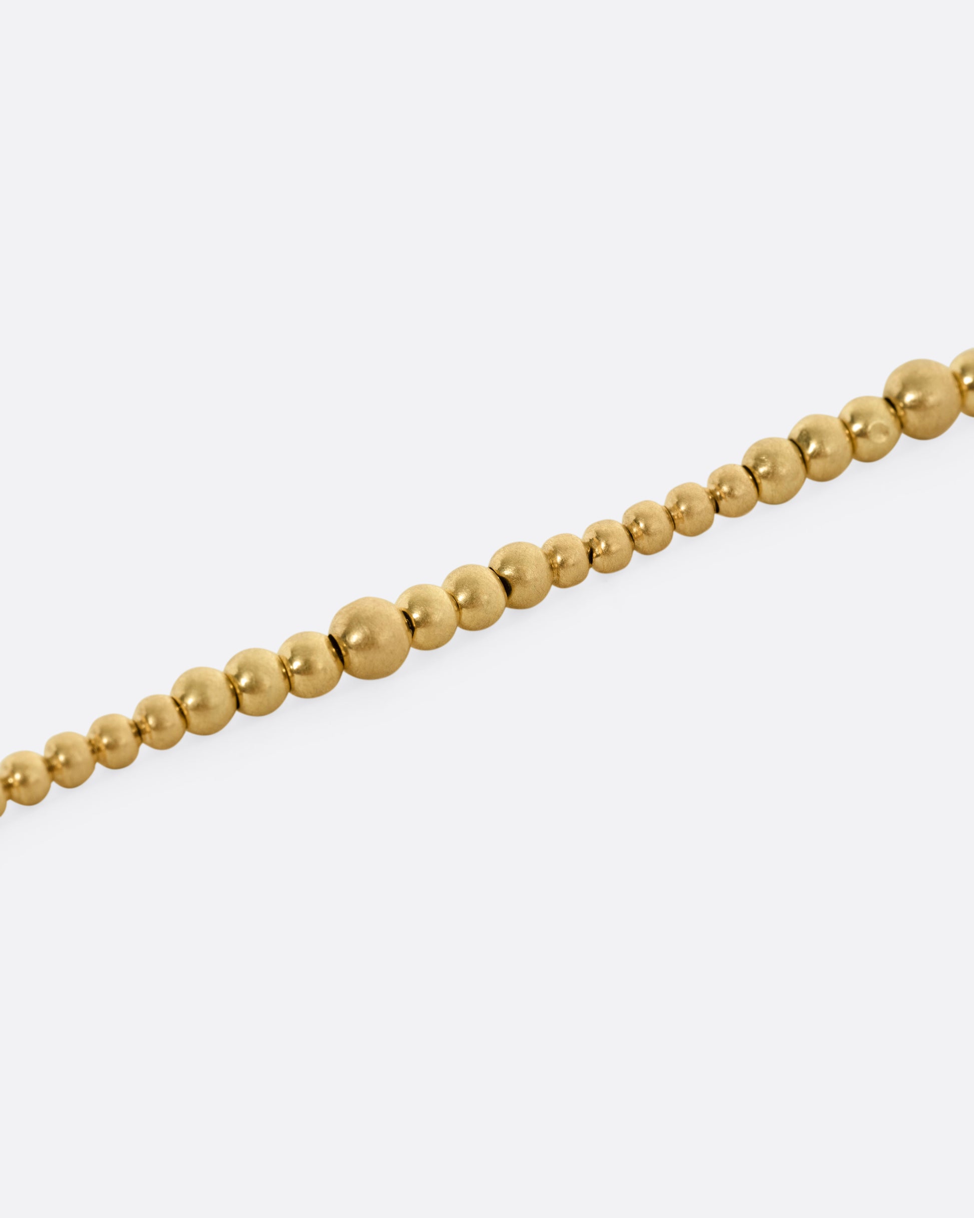 A close up of a yellow gold bracelet with graduated beads.