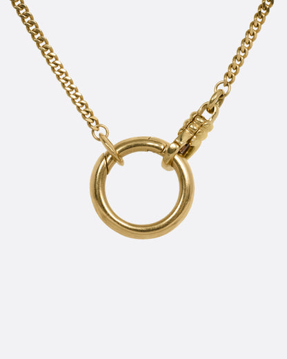 A close up of a yellow gold cable chain with an asymmetrical side bail and a central knife-edged hoop, both for charms. Shown from the front.
