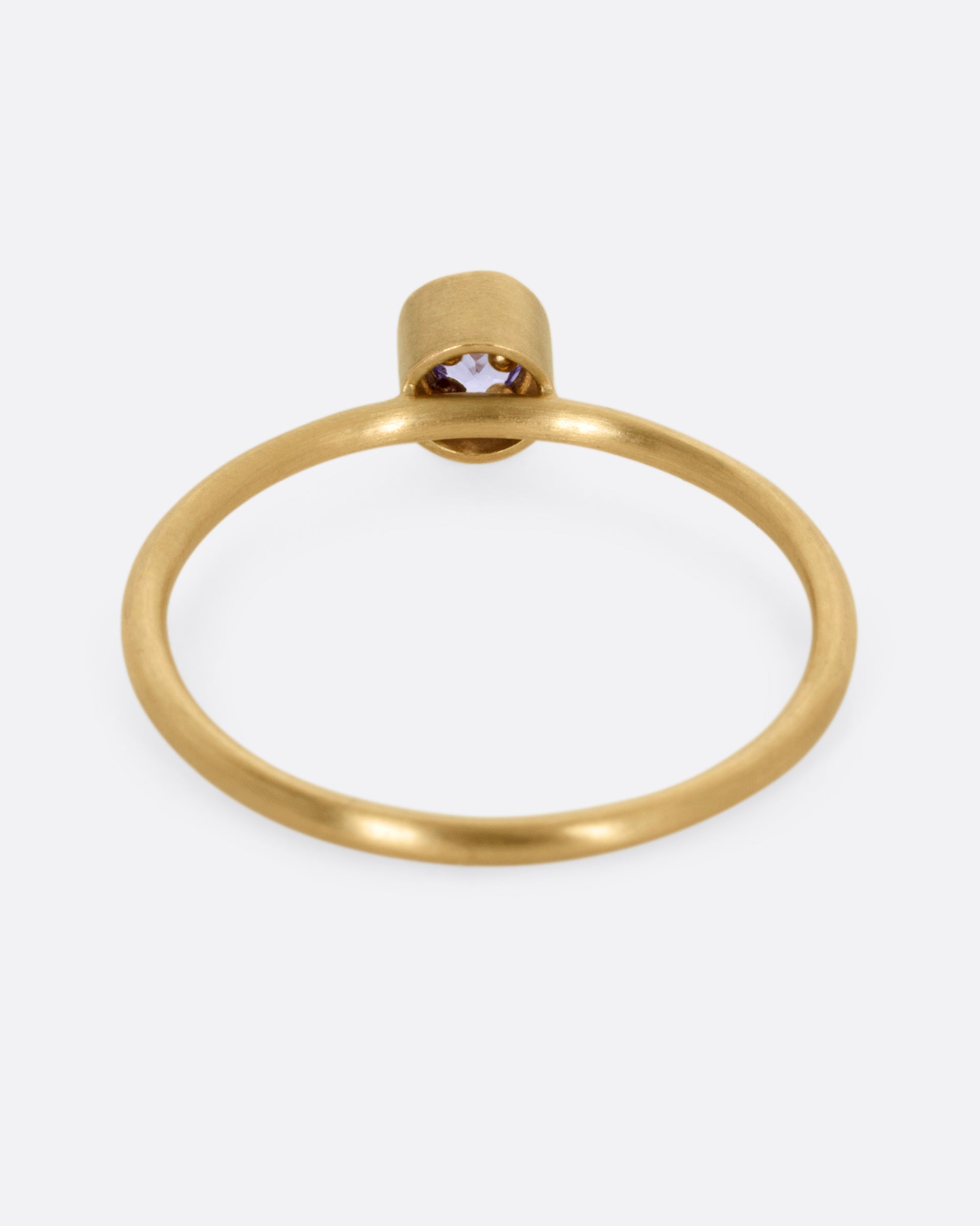 A yellow gold ring with a tanzanite in a raised bezel, shown from the back.