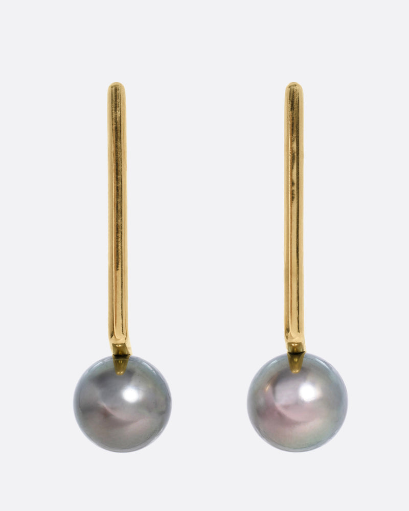 A pair of yellow gold stud earrings with an angular bar and dark grey pearl, shown from the front.