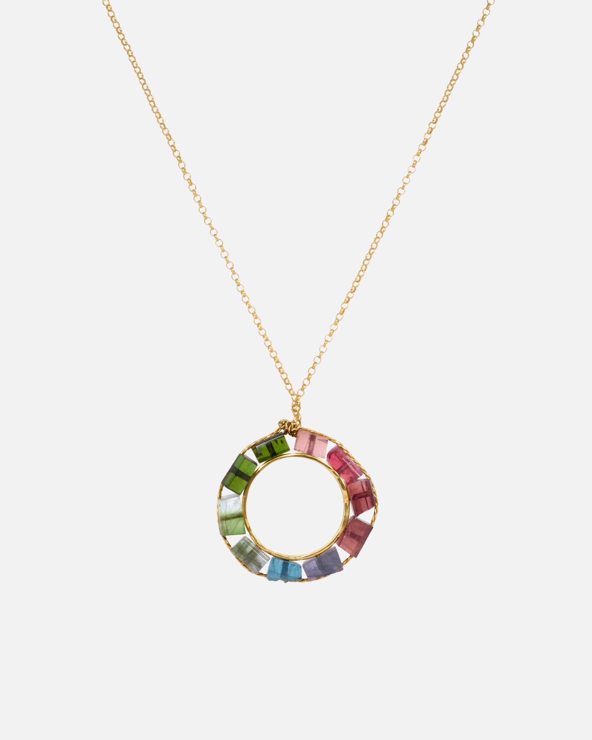 A yellow gold cable chain necklace with an open circular pendant featuring multicolored tourmalines. Shown from the front.