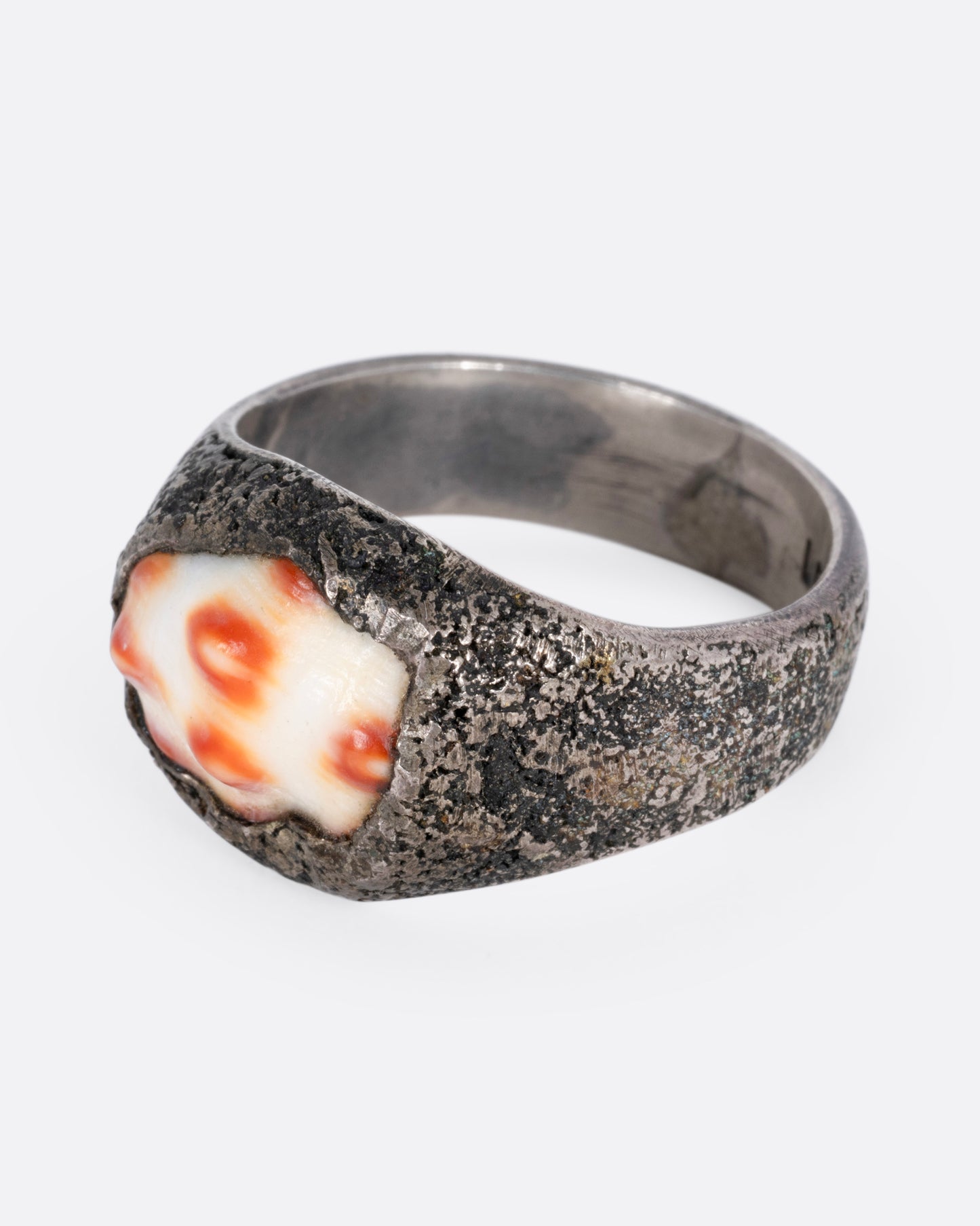 A silver signet ring with a speckled shell, shown from the side.
