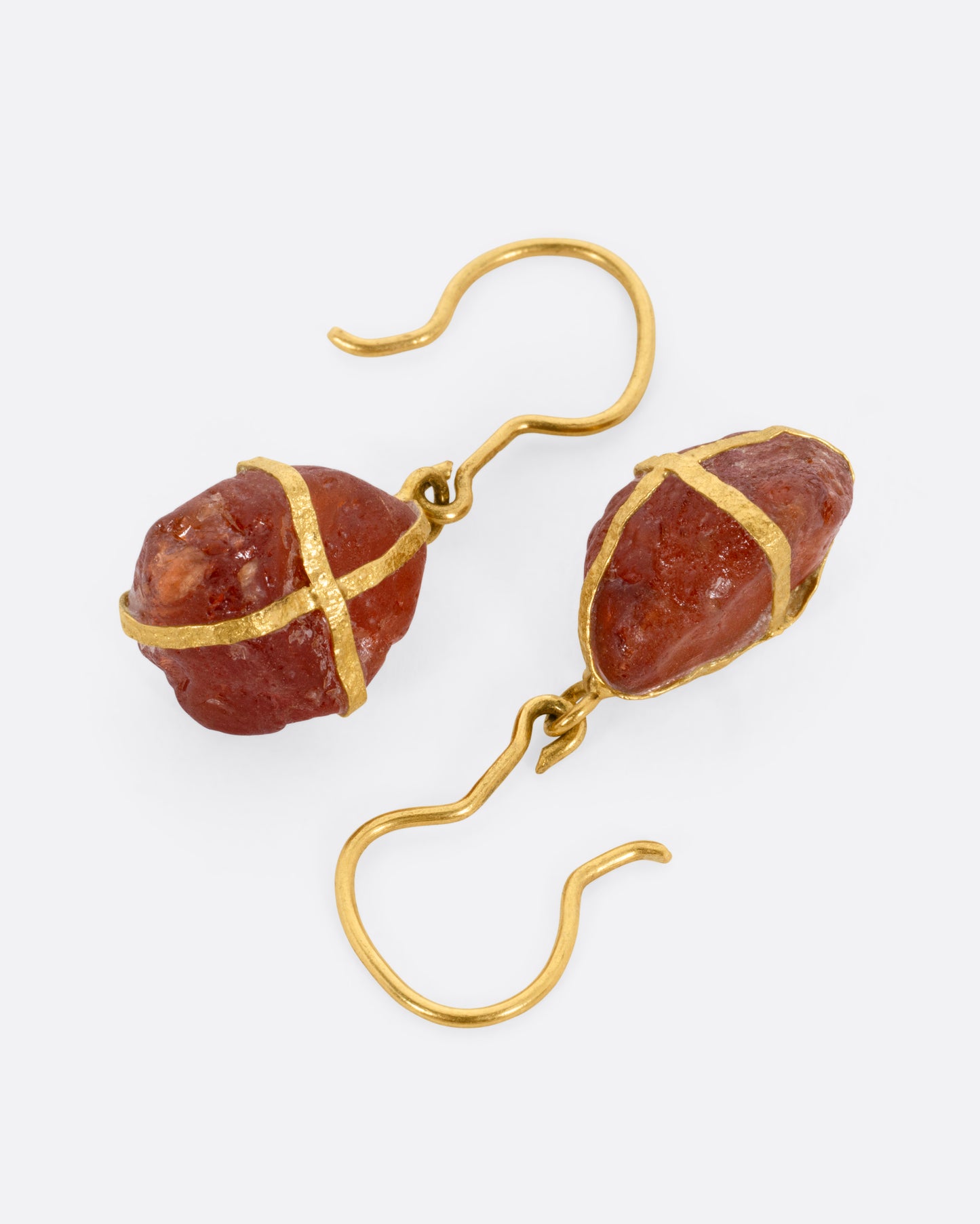 A pair of yellow gold drop earrings with gold wrapped raw rubelites, shown from the side.