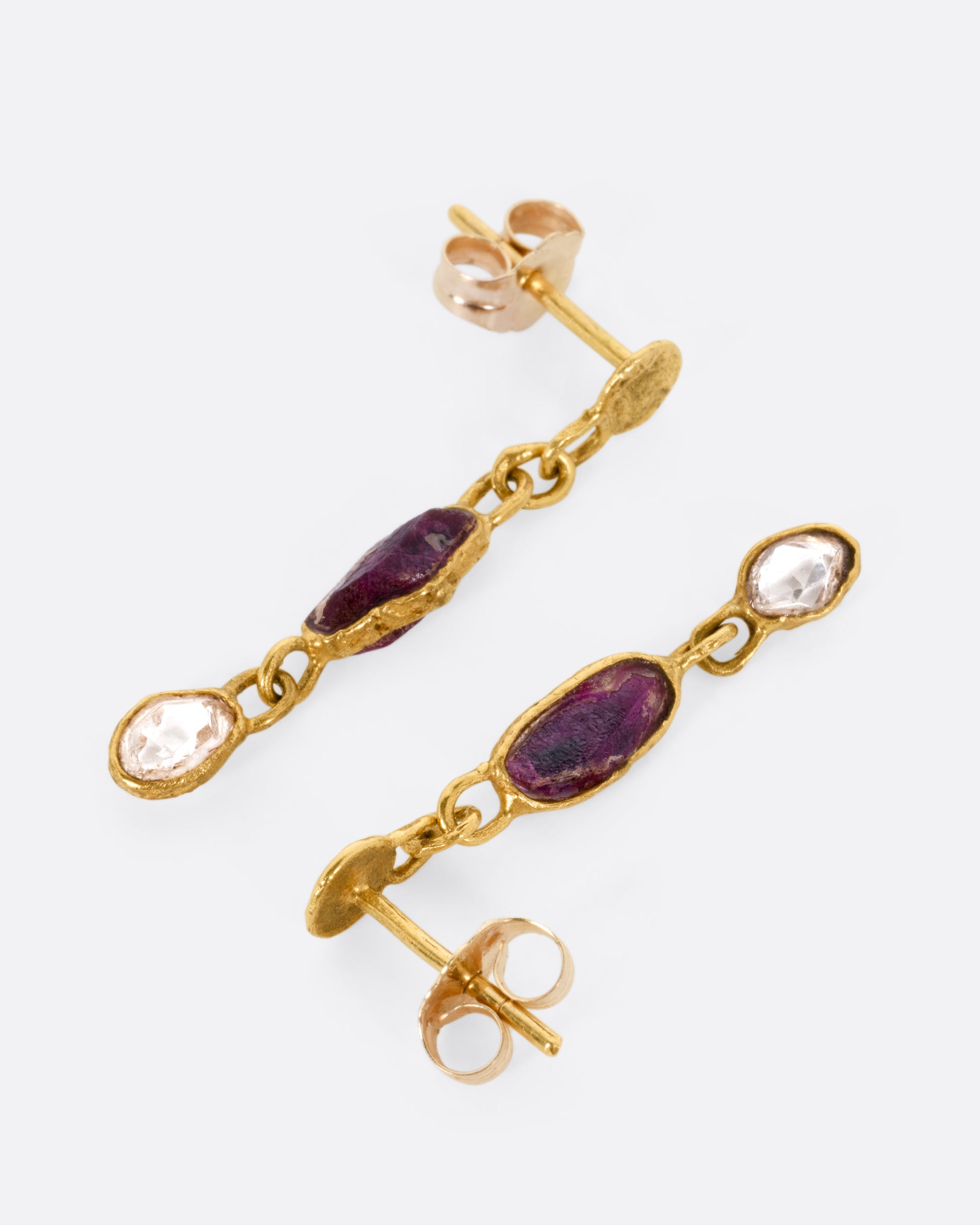 A pair of yellow gold earrings with sapphires and diamonds, shown lying on their sides.