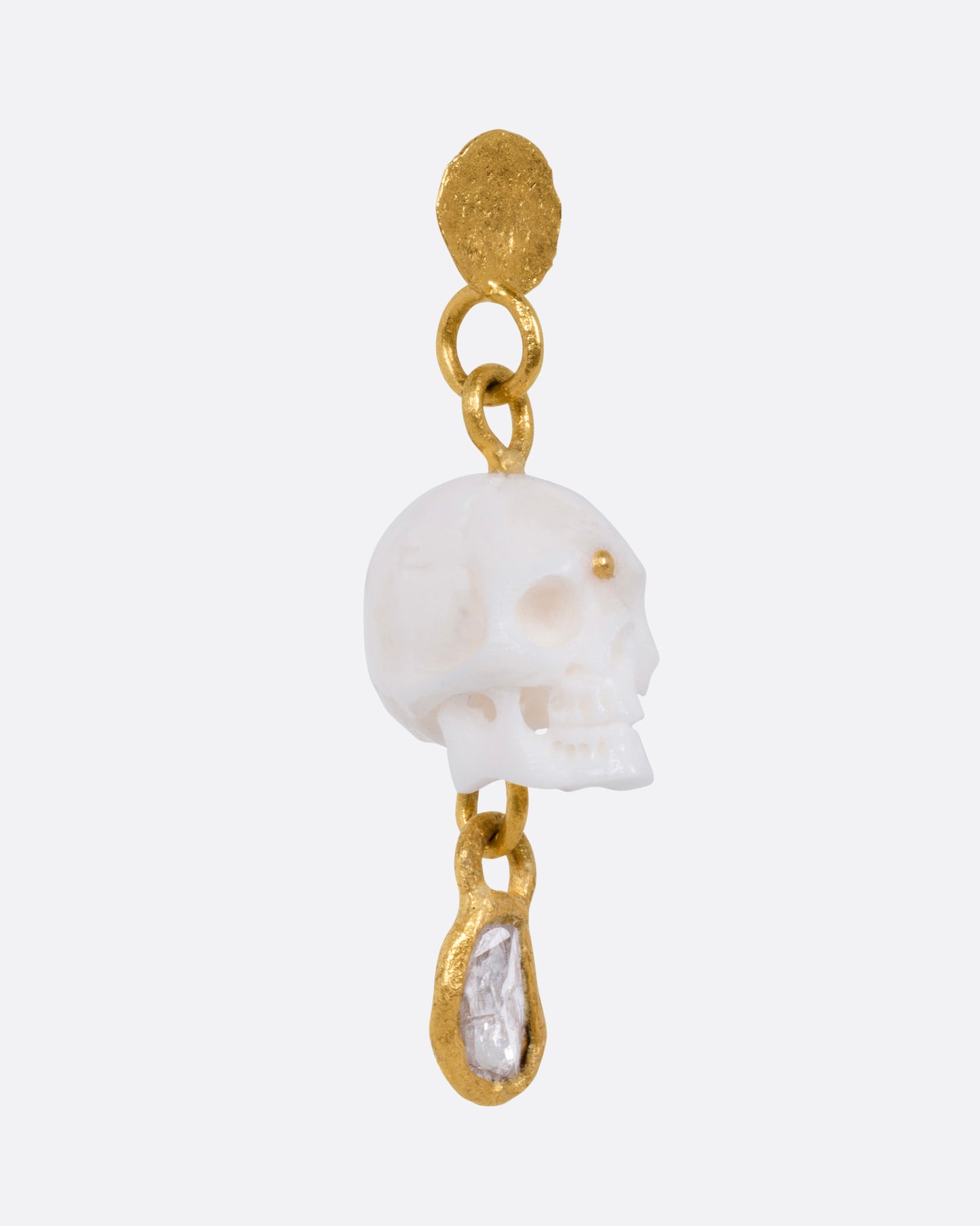 A yellow gold drop stud earring with a carved bone skull and a Borneo diamond, shown from the side.
