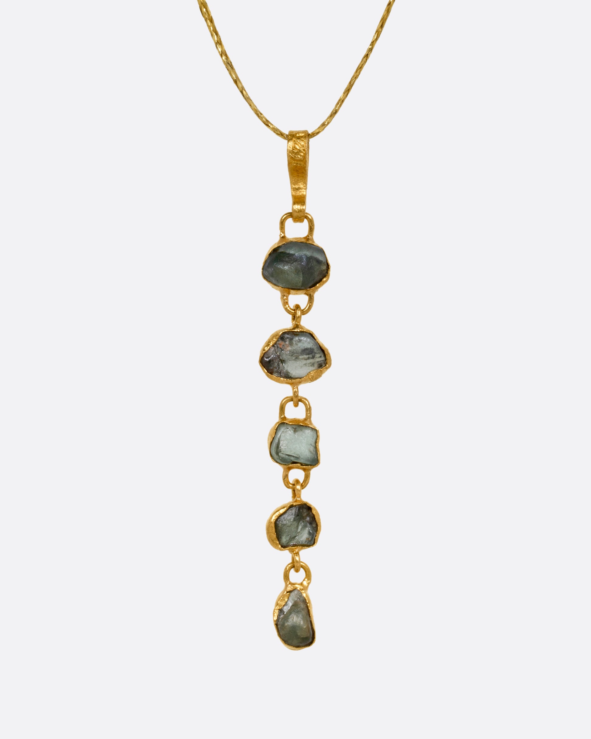 A yellow gold pendant with five Montana sapphires on a cord, shown from the front.