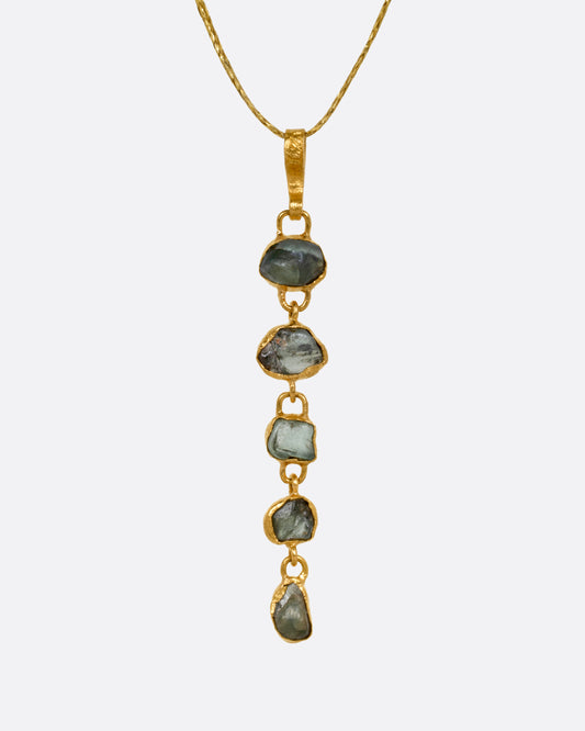 A yellow gold pendant with five Montana sapphires on a cord, shown from the front.