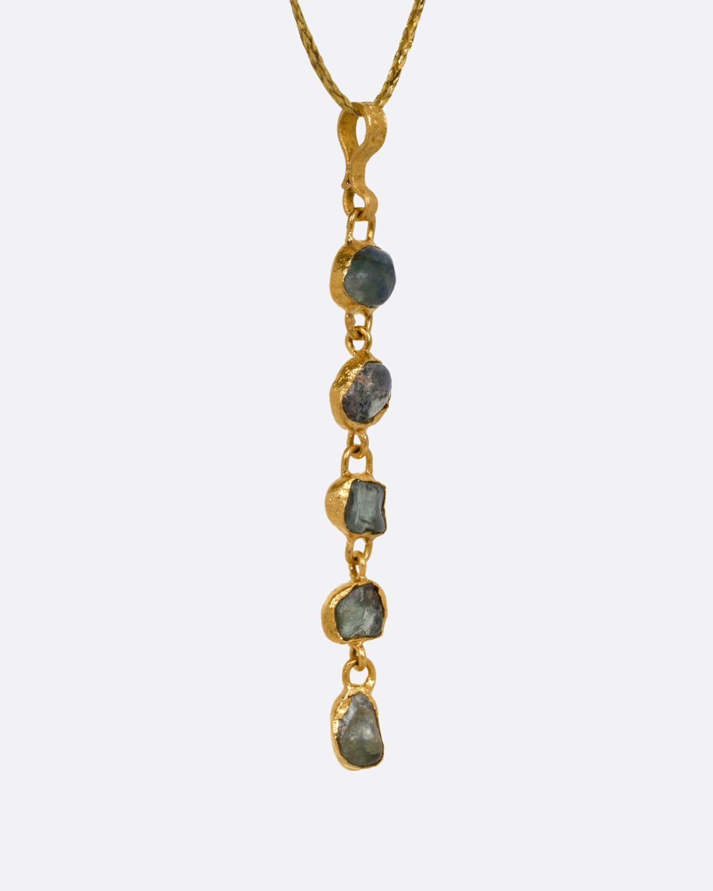 A yellow gold pendant with five Montana sapphires on a cord, shown from the side.
