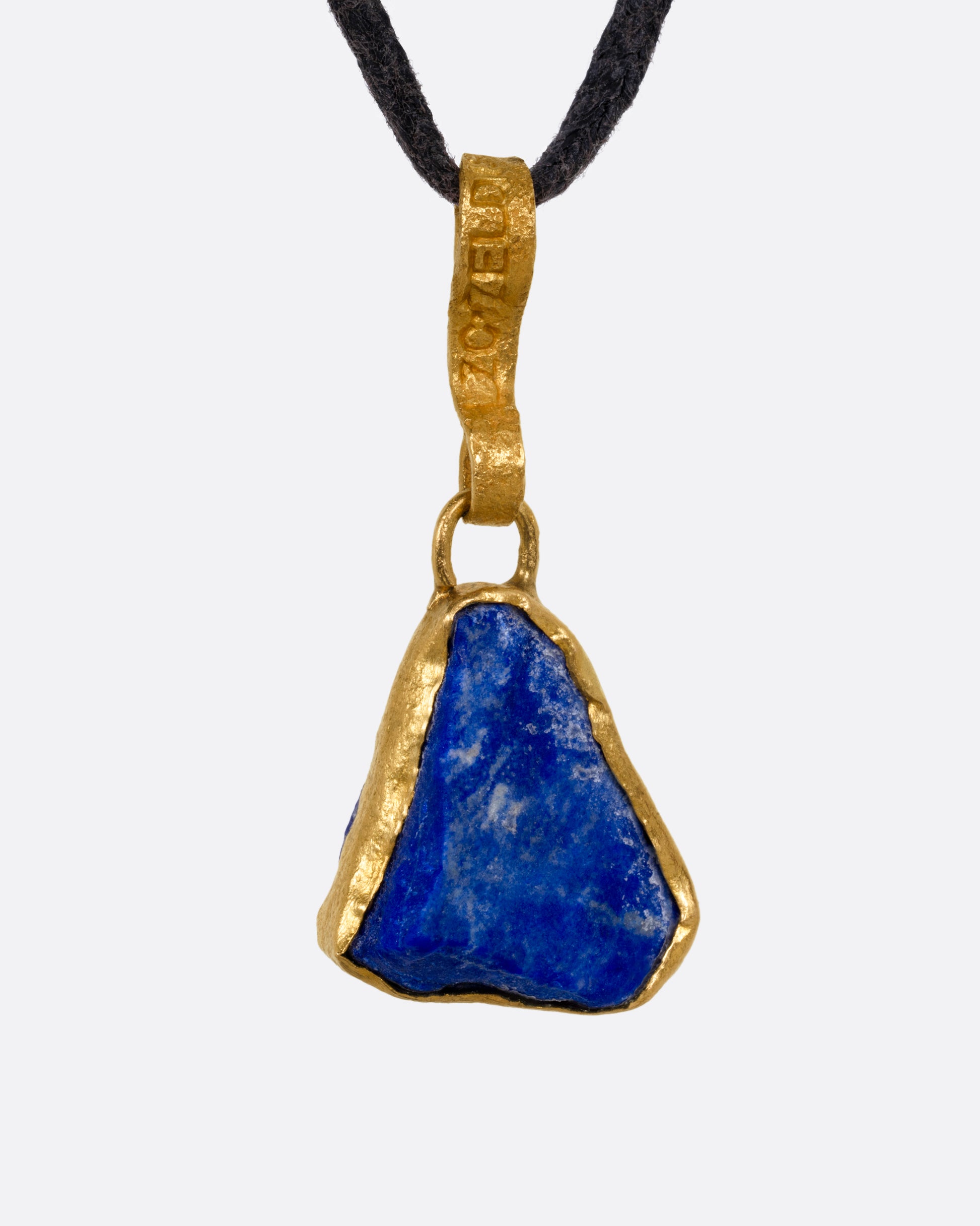 A yellow gold pendant with a raw triangular lapis on a black cord, shown from the front.