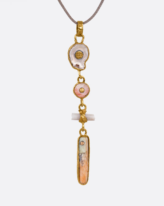 A yellow gold pendant with four gold wrapped pieces on a cord, shown from the front.