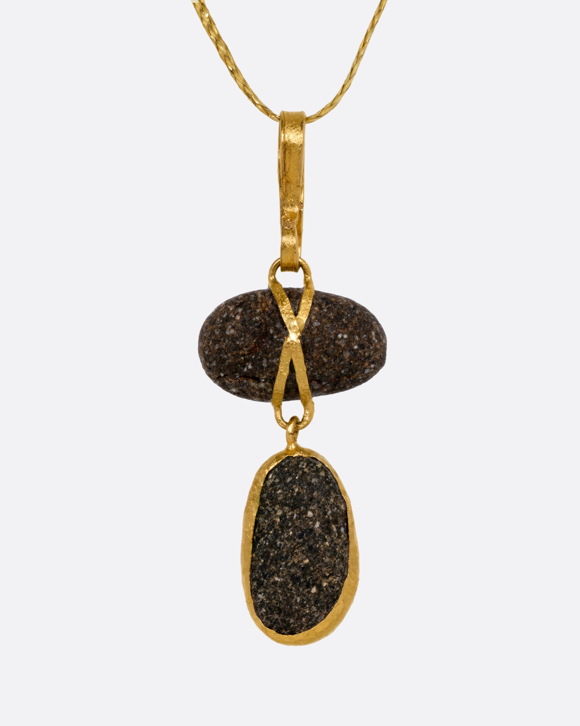 A yellow gold pendant with two Japanese river pebbles on a cord, shown from the front.