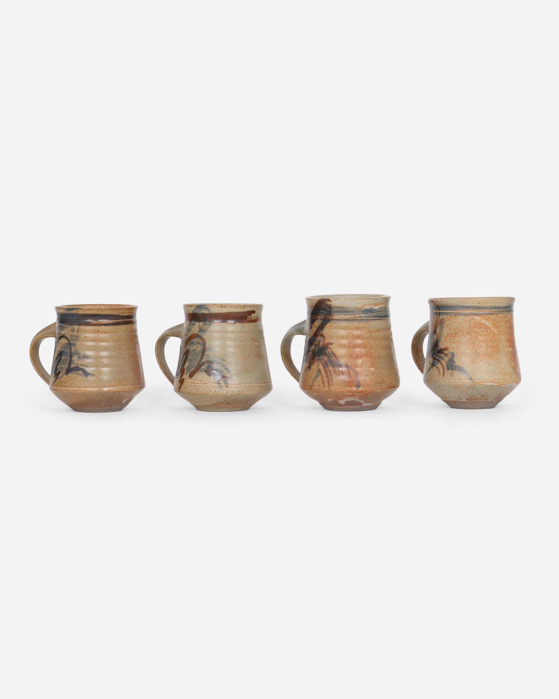Four handmade ceramic mugs with blue and brown brushstrokes. Shown from the back.