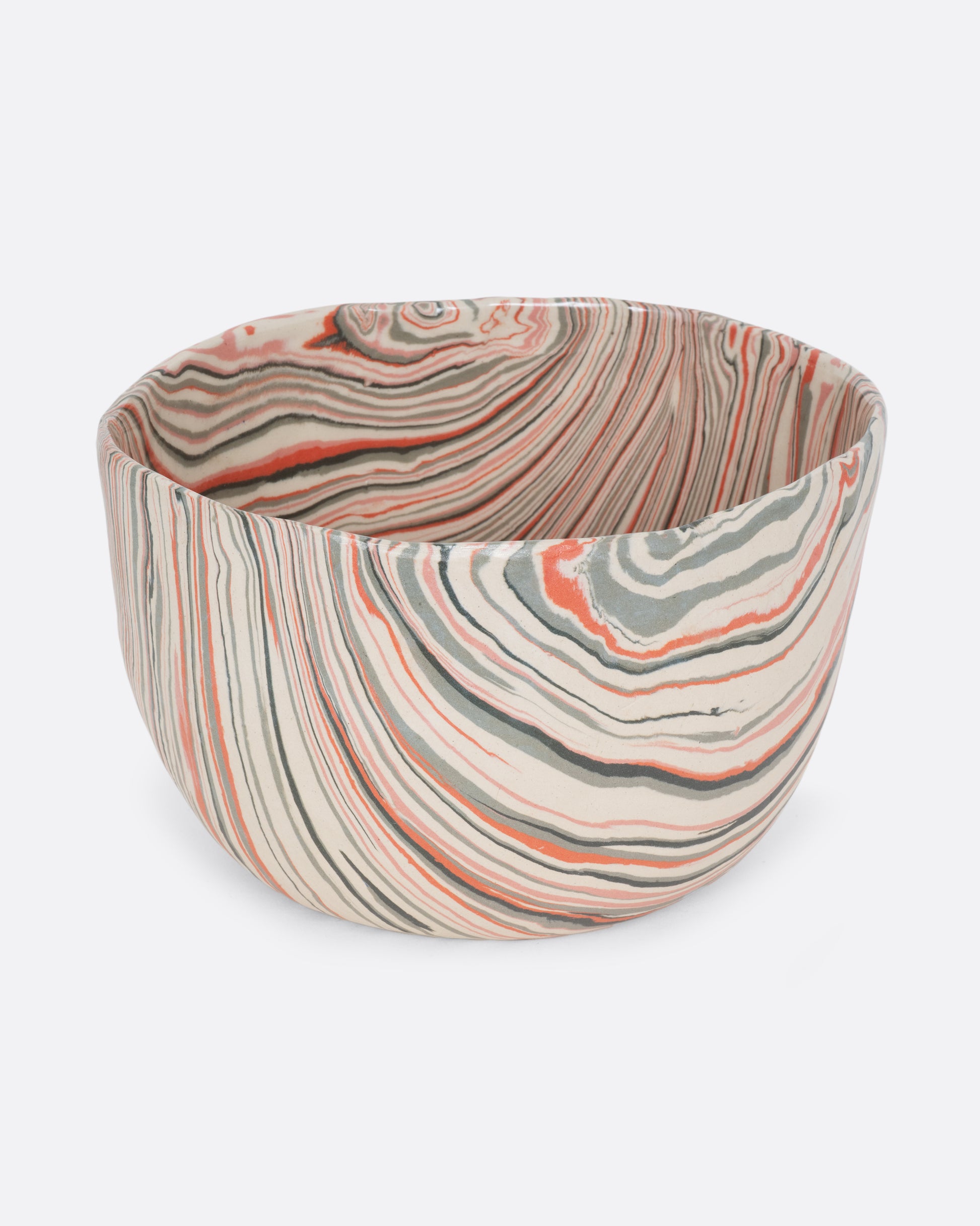 A ceramic bowl with peach, gray, and cream swirls. Shown from the side.