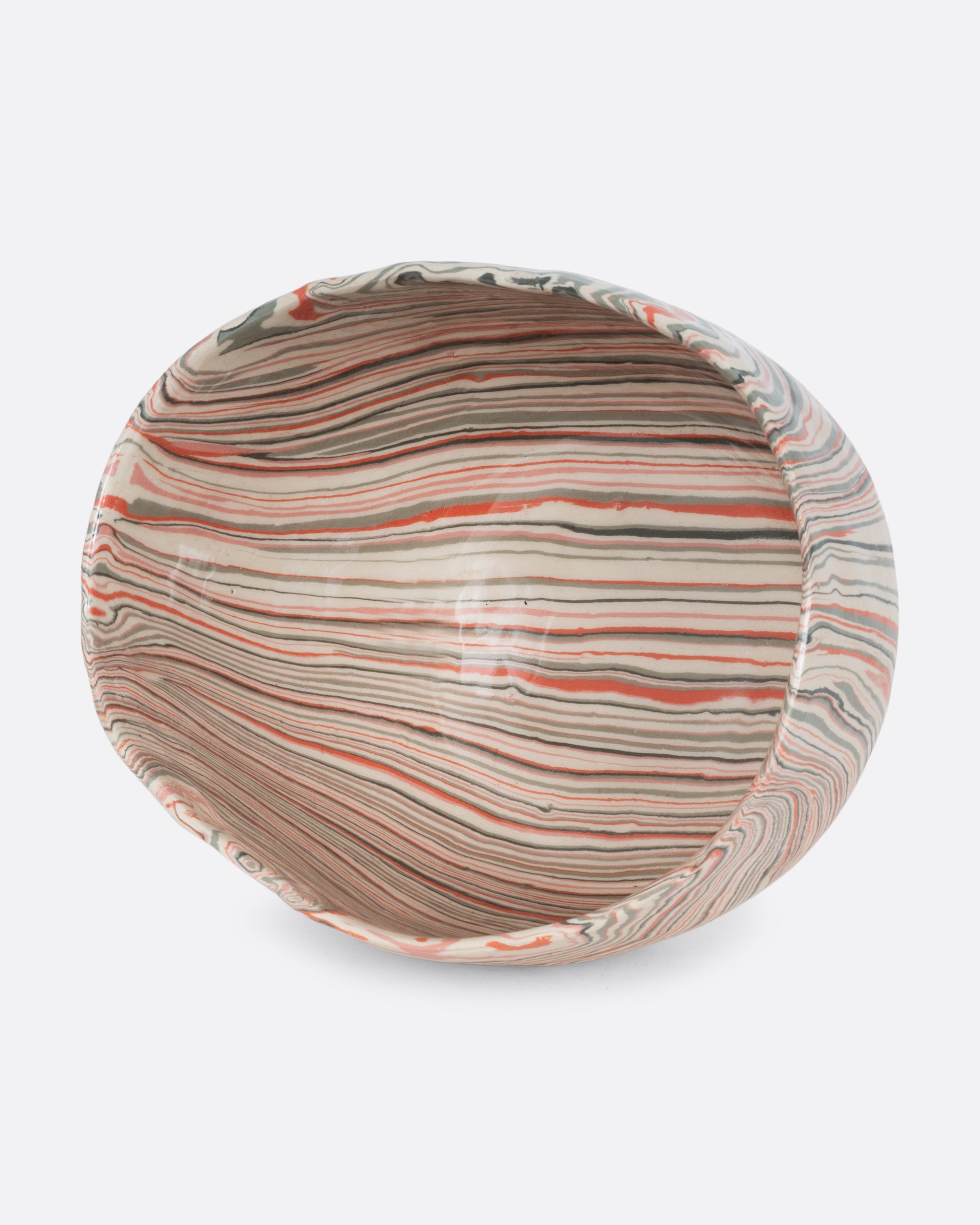 A ceramic bowl with peach, gray, and cream swirls. Shown on its side from the top.