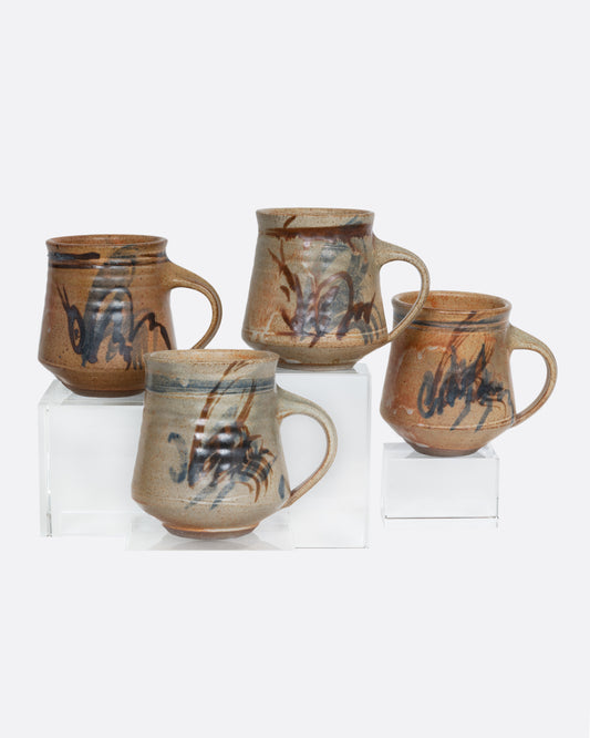 Four handmade ceramic mugs with blue and brown brushstrokes. Shown from the side.