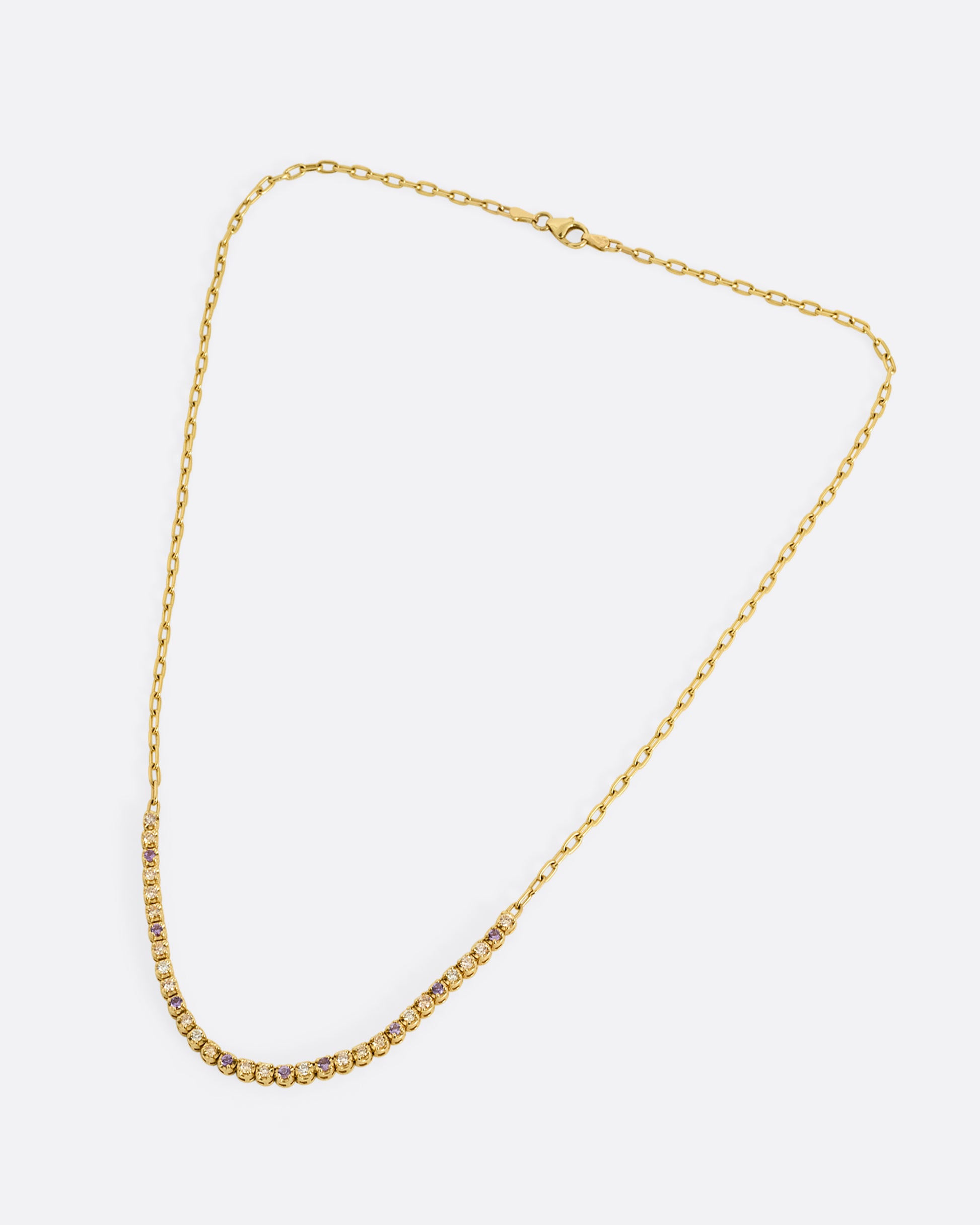 A yellow gold cable chain necklace with peach and yellow diamonds and purple sapphires in a 'partial tennis' setting. Shown closed lying flat from the front.