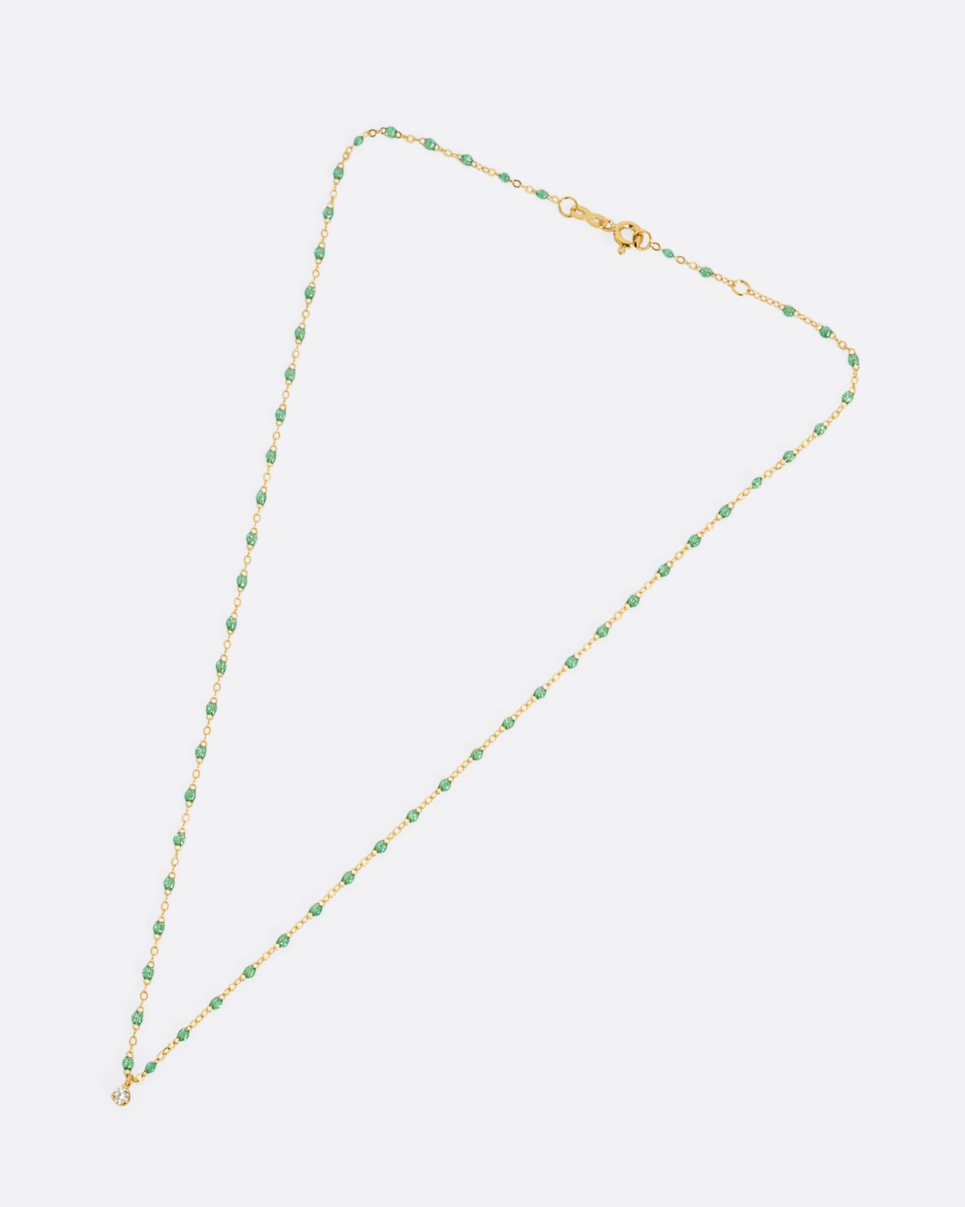 A yellow gold cable chain necklace with mint green resin droplets and a diamond charm at the center. Shown clasped lying flat from the front.
