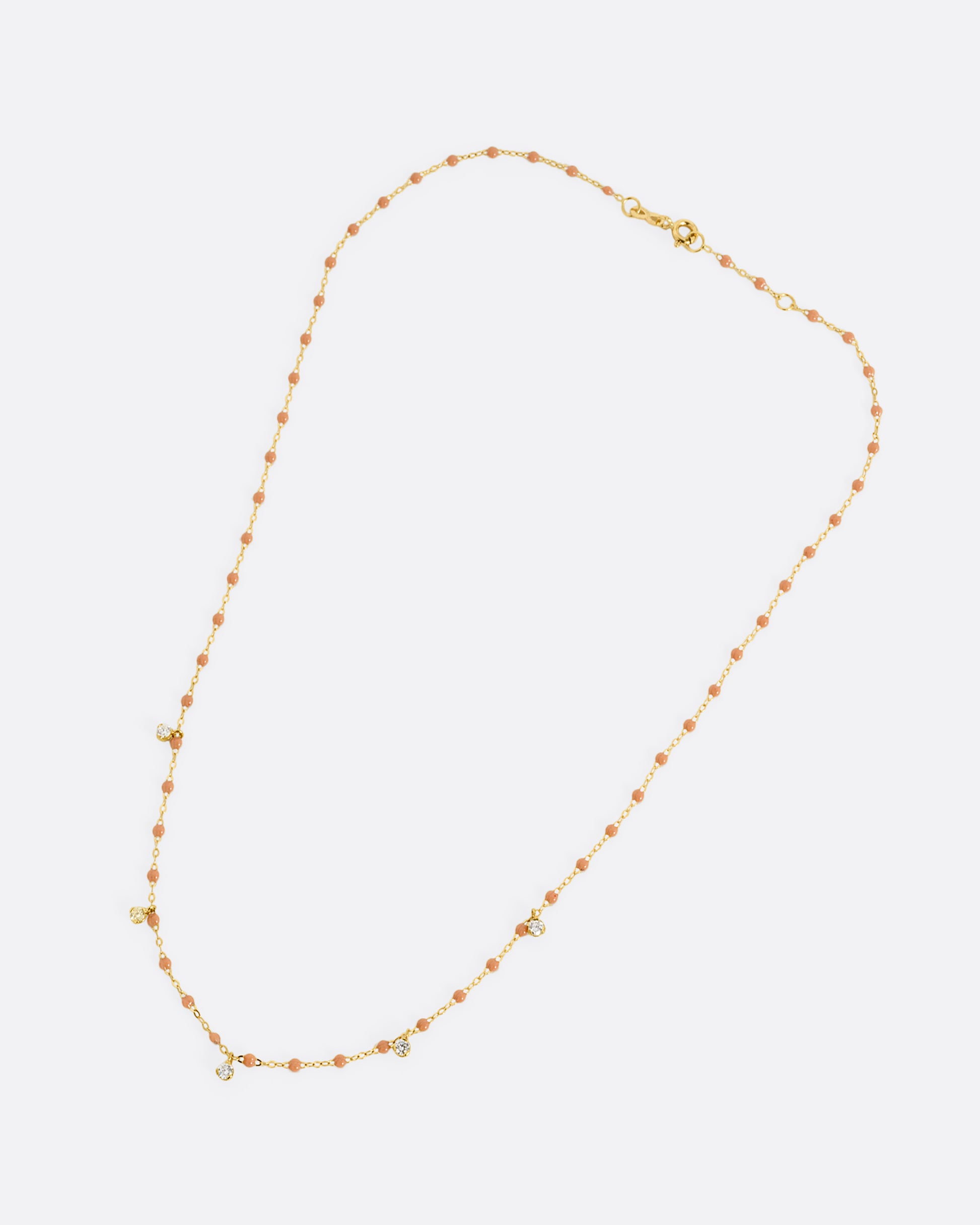 A yellow gold cable chain necklace with caramel brown resin droplets along the chain and five dangling diamond charms. Shown closed lying flat from the front.