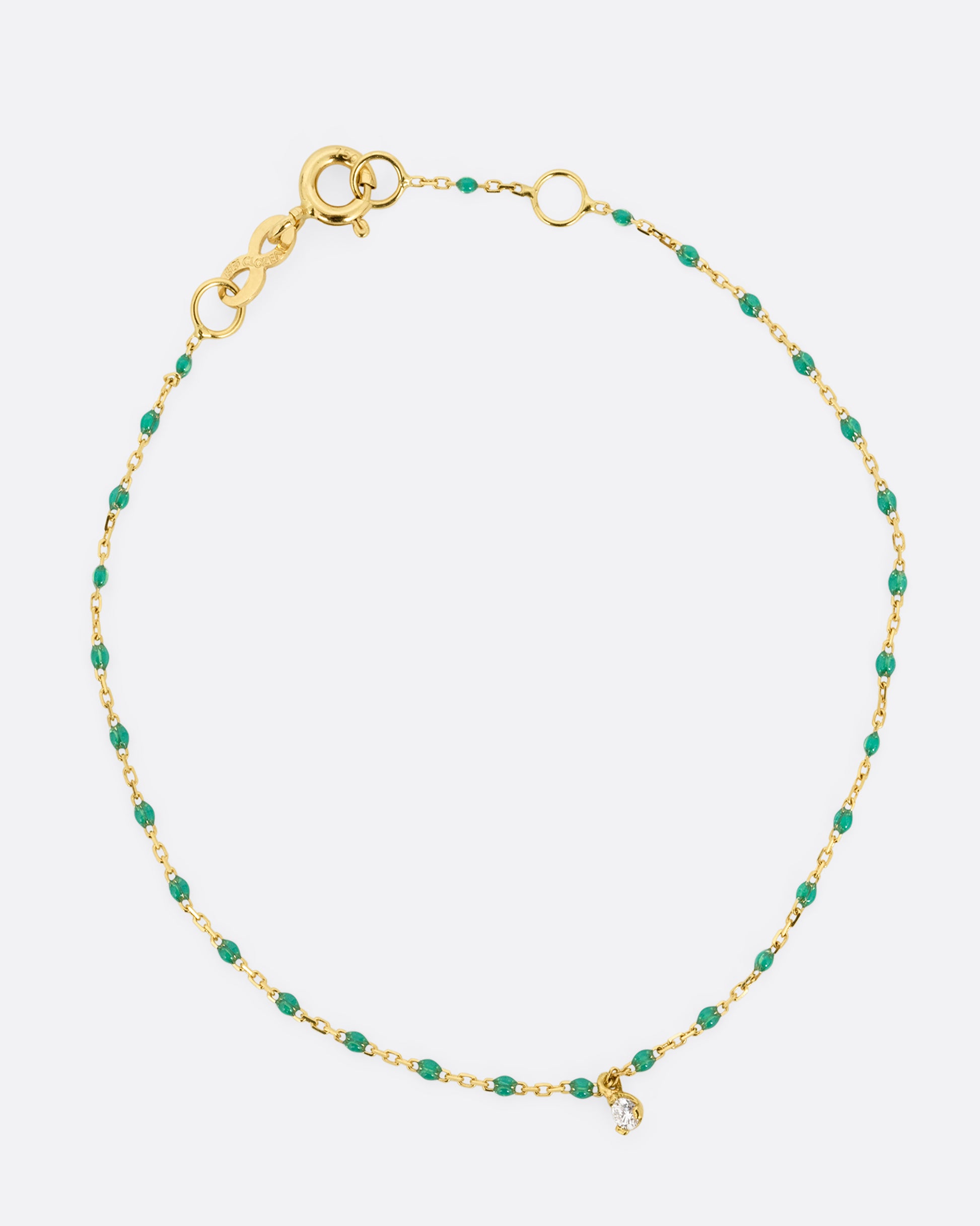 A yellow gold cable chain bracelet with green resin droplets throughout and a single diamond charm. Shown from the front.