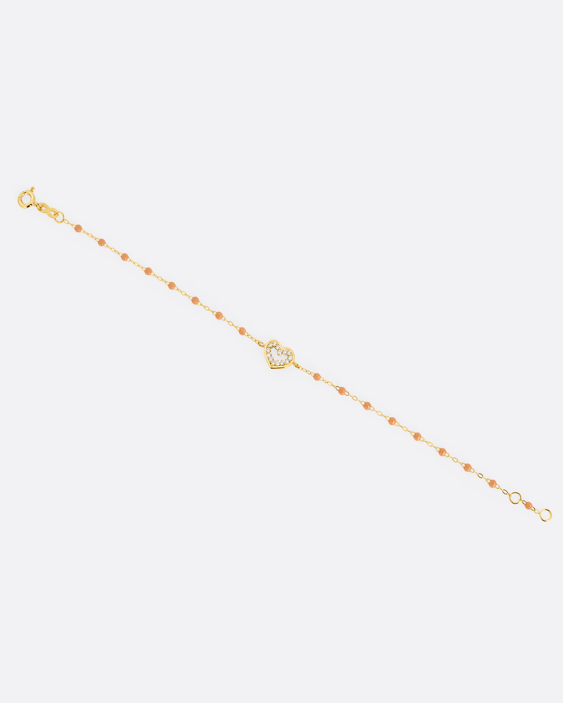 A yellow gold cable chain bracelet with a diamond lined heart charm and caramel brown resin droplets throughout. Shown from the front.
