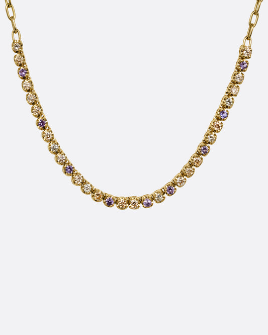 A yellow gold cable chain necklace with peach and yellow diamonds and purple sapphires in a 'partial tennis' setting. Shown from the front.