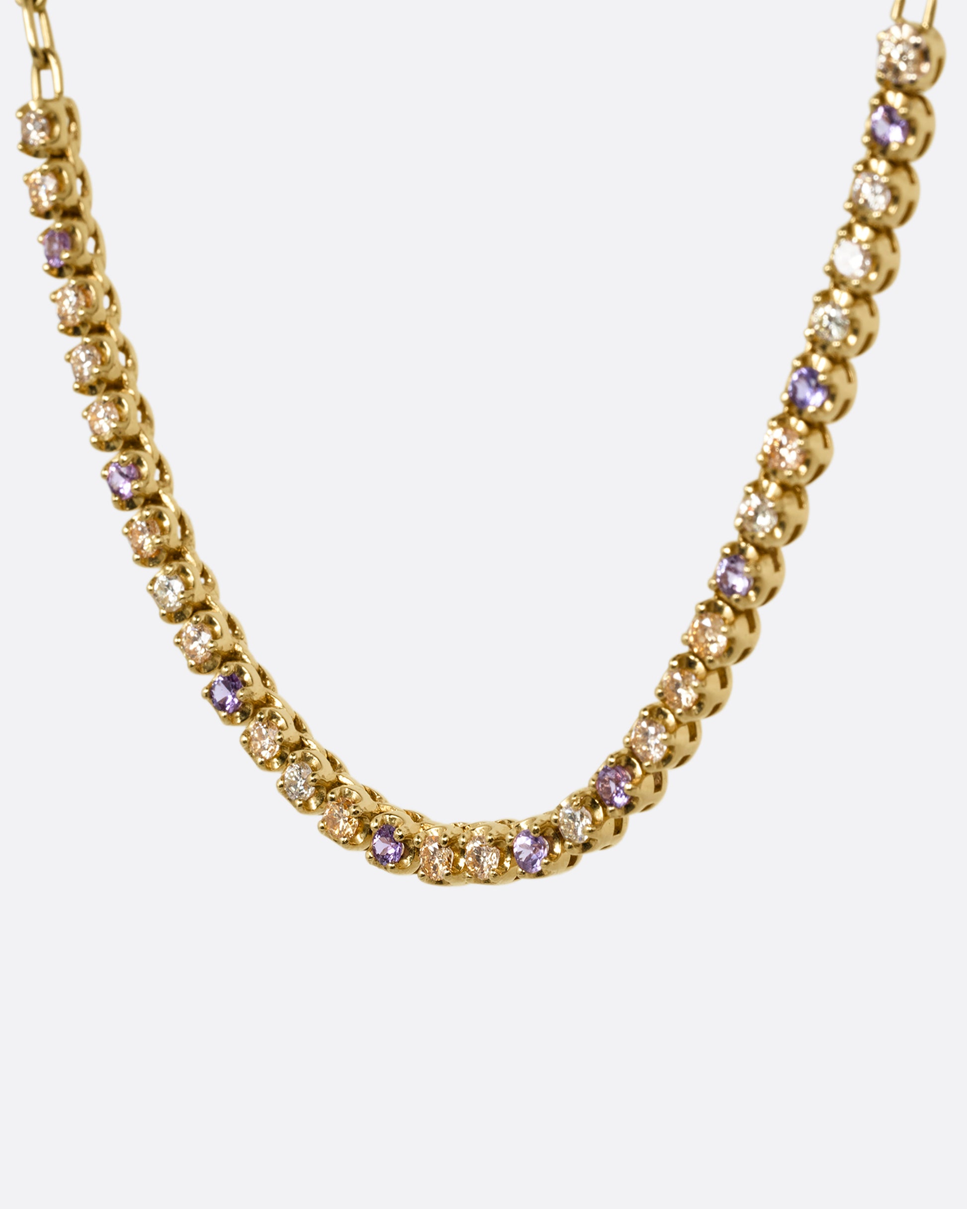 A yellow gold cable chain necklace with peach and yellow diamonds and purple sapphires in a 'partial tennis' setting. Shown from the side.