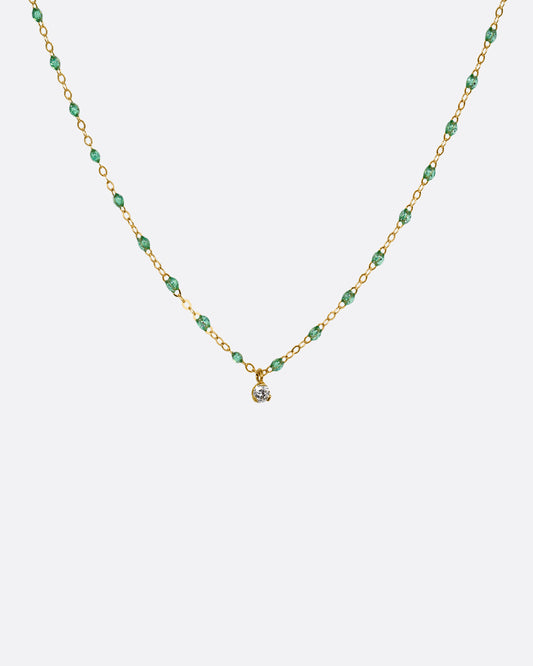 A yellow gold cable chain necklace with mint green resin droplets and a diamond charm at the center. Shown from the front.