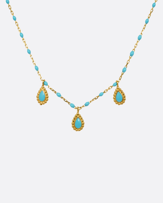 A yellow gold cable chain necklace with turquoise resin droplets along the chain and three teardrop shaped gold charms with turquoise resin centers. Shown from the front.