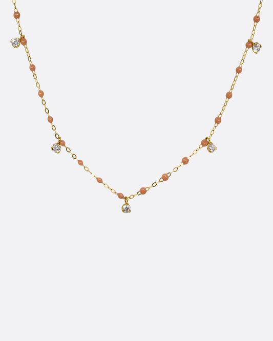 A yellow gold cable chain necklace with caramel brown resin droplets along the chain and five dangling diamond charms. Shown from the front.