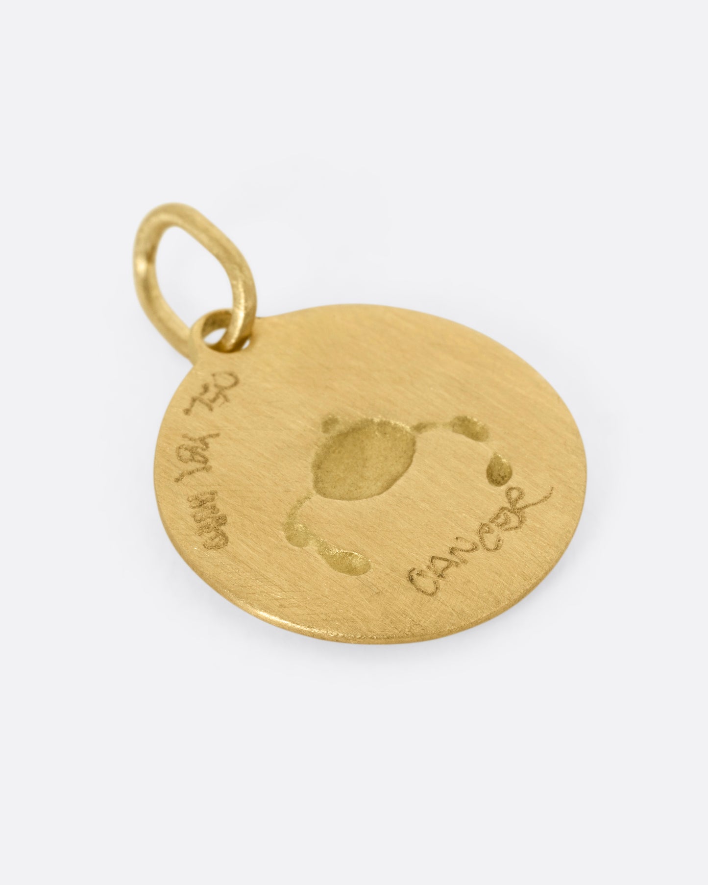 A circular yellow gold Cancer pendant with a crab on its front, shown from the back.