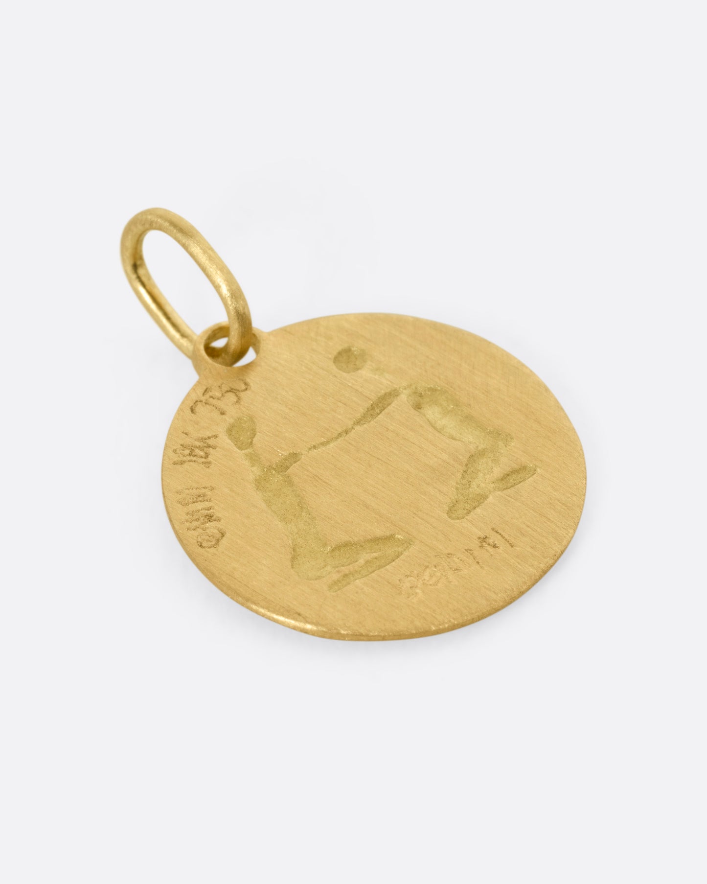 A circular yellow gold Gemini pendant with the twins, shown from the back.