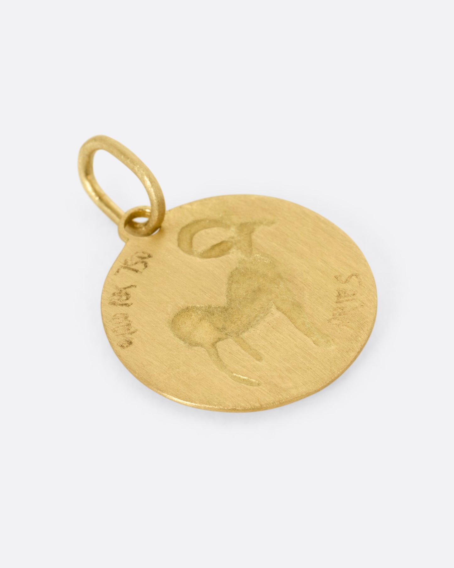A yellow gold circular Aries pendant with a ram, shown from the back.