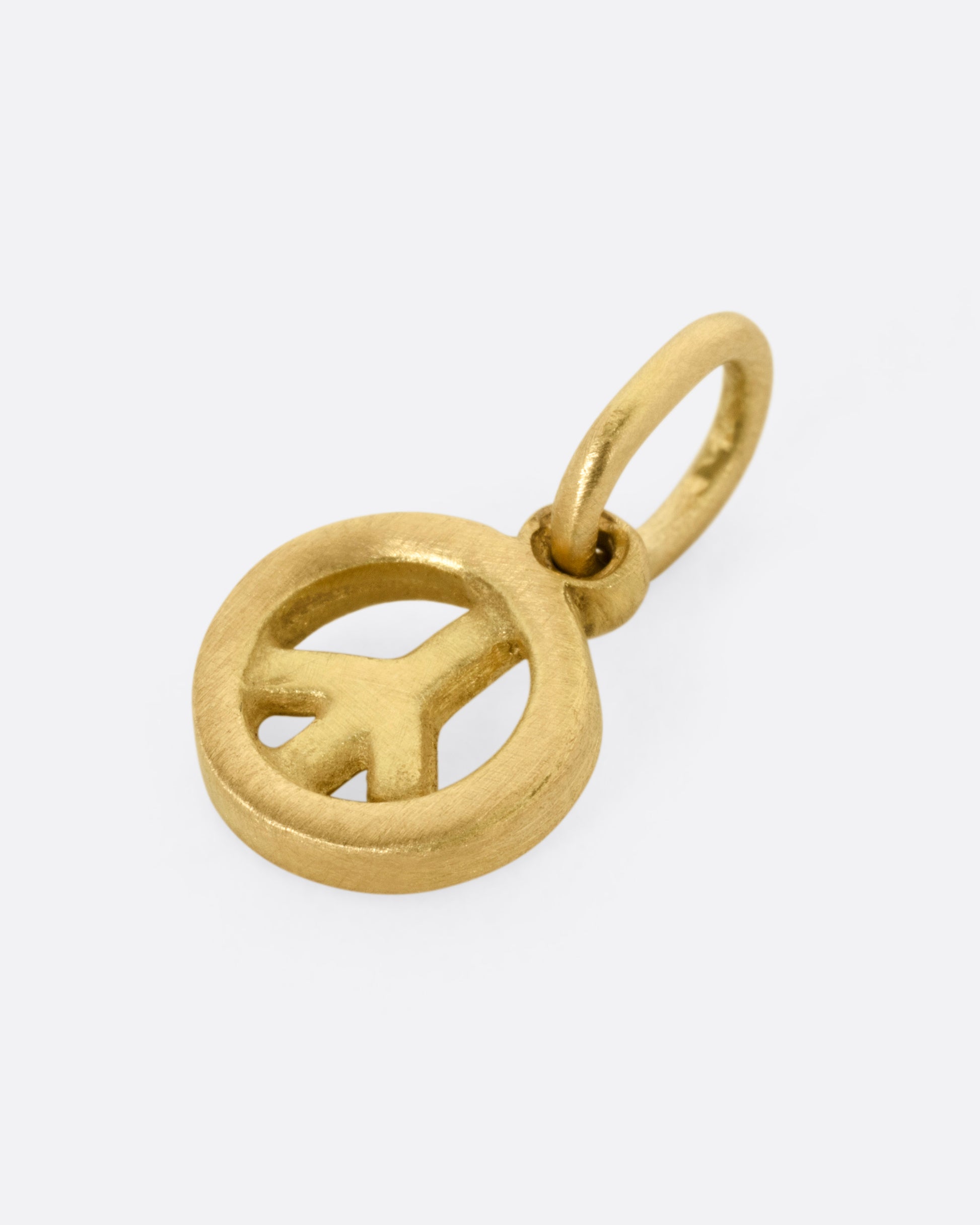 A yellow gold peace sign pendant shown from the side.