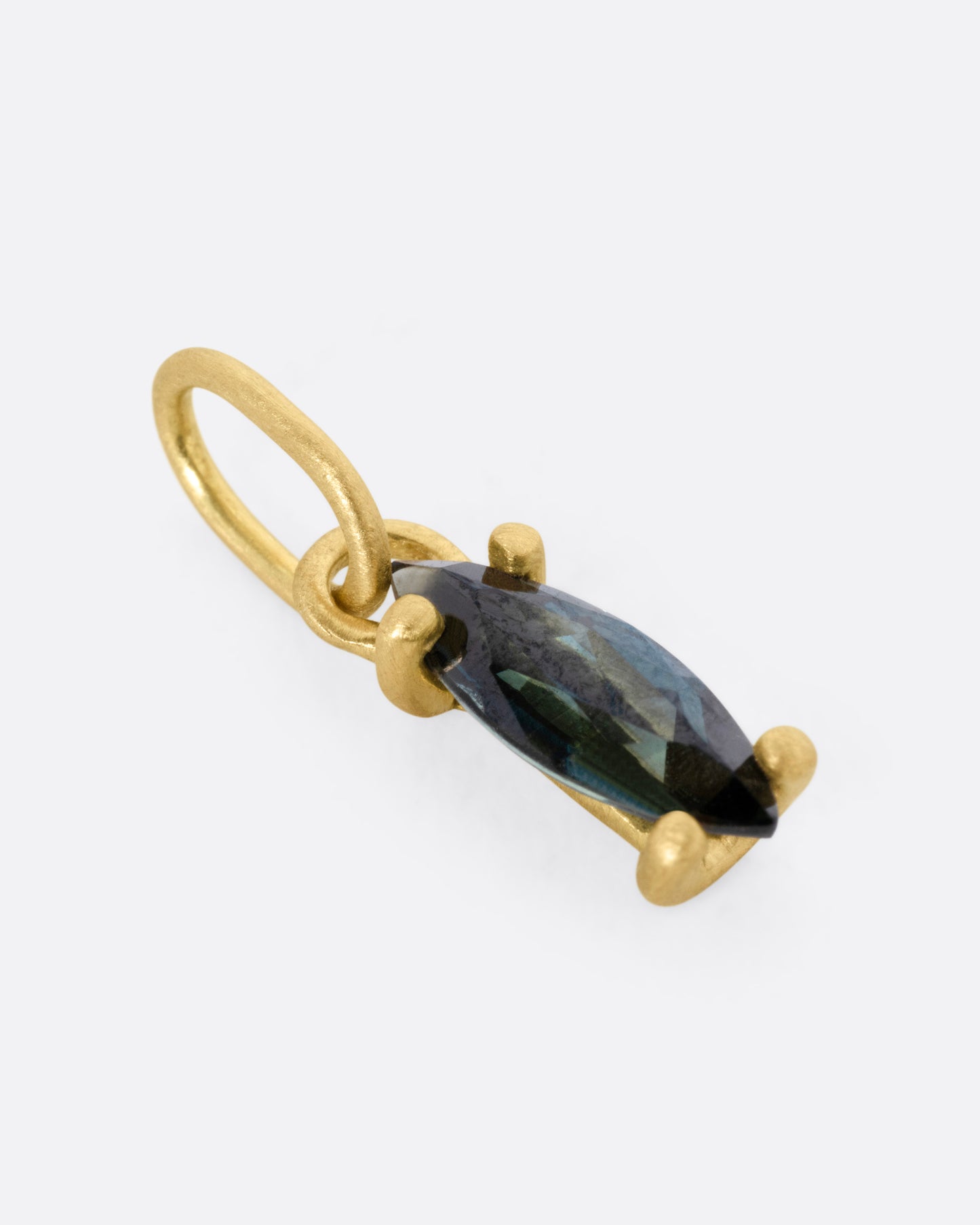 A yellow gold pendant with a blue marquise sapphire, shown from the side.