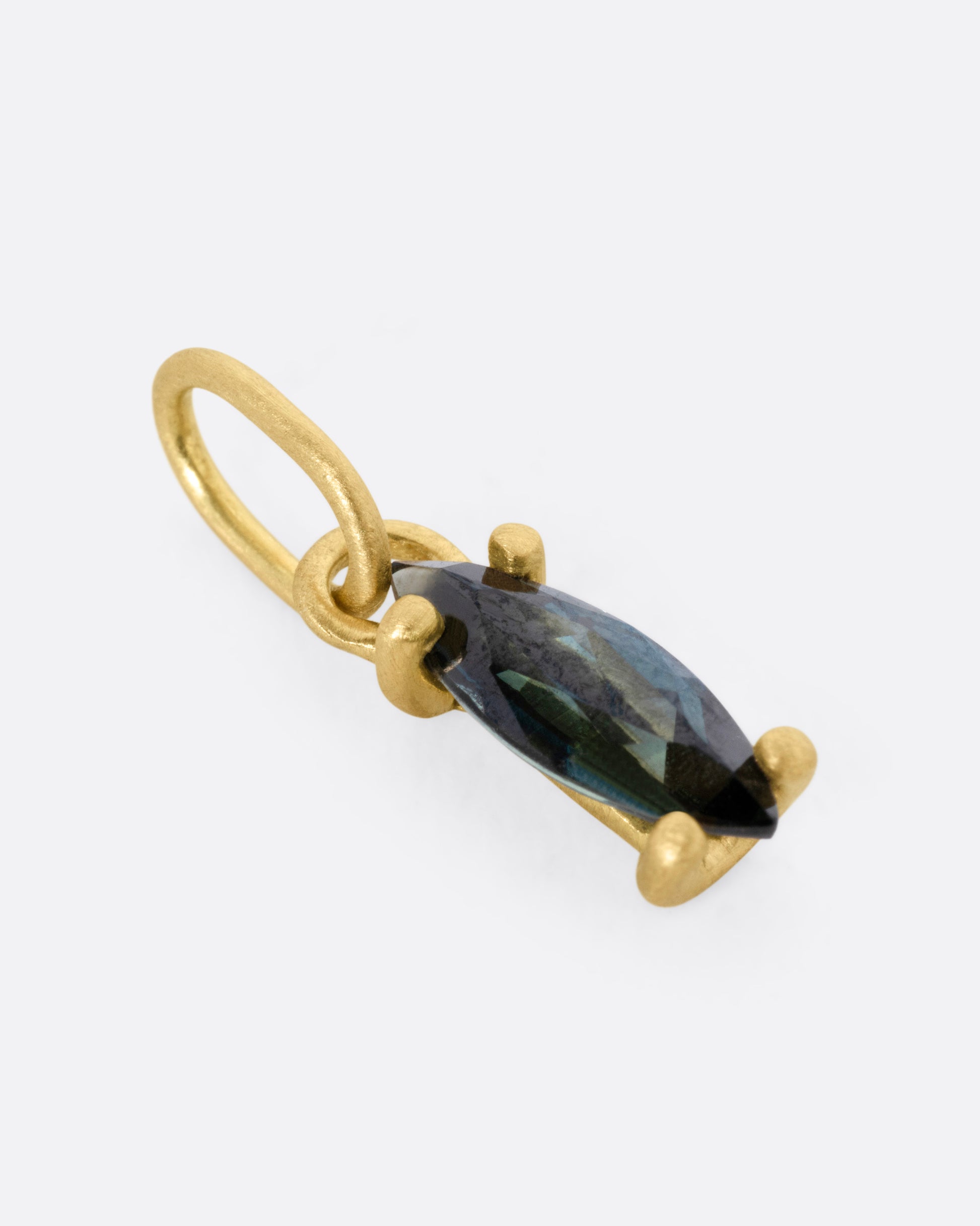 A yellow gold pendant with a blue marquise sapphire, shown from the side.