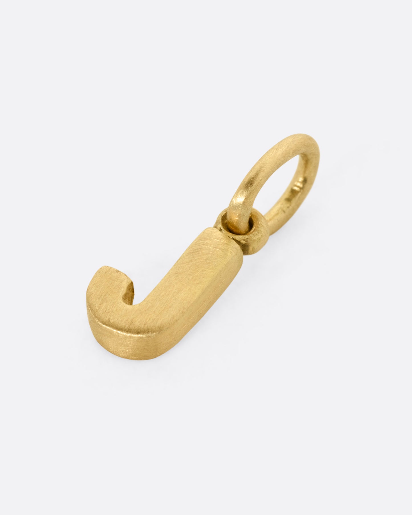 A yellow gold letter 'J' pendant shown from the side.