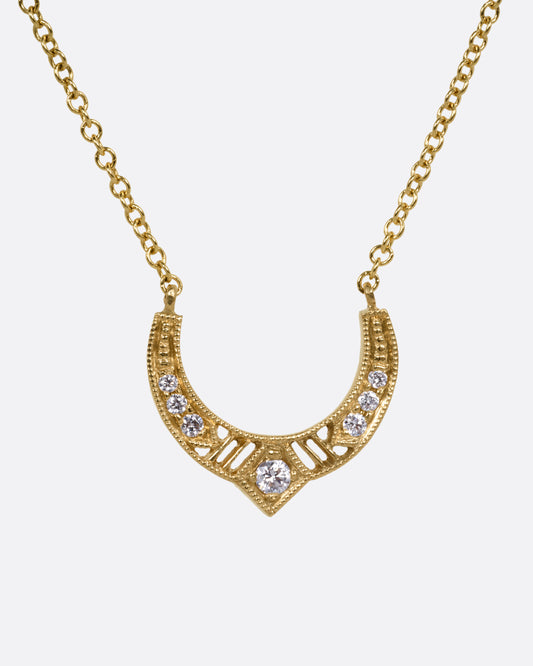 A yellow gold necklace with an arched pendant with diamonds and cutouts, shown from the front.