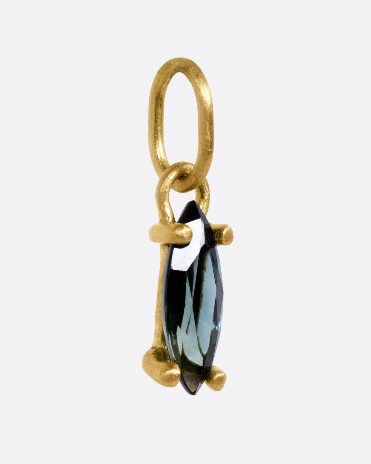 A yellow gold pendant with a blue marquise sapphire, shown from the side.