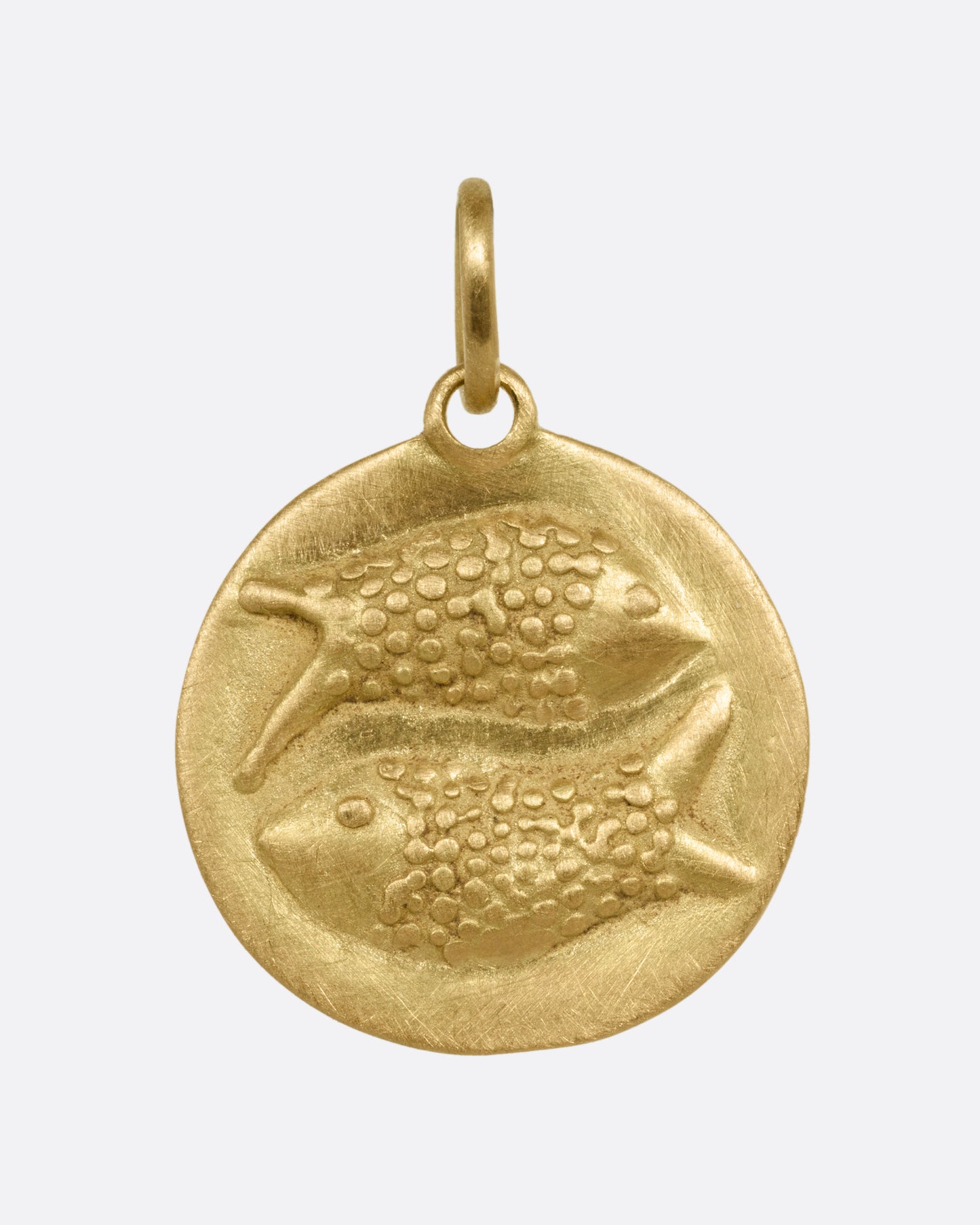 A circular yellow gold Pisces pendant with two fish on its front, shown from the front.