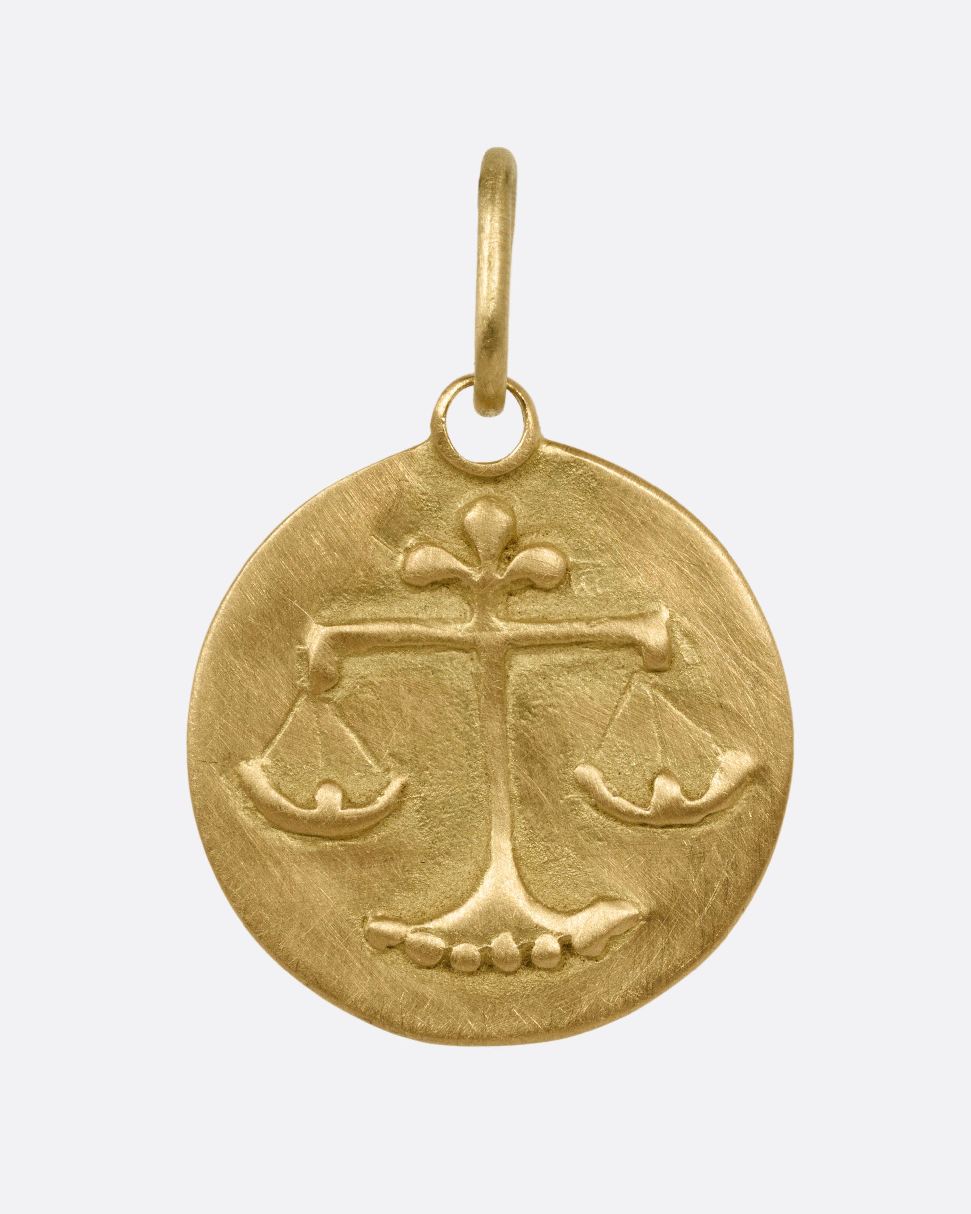 A circular yellow gold Libra pendant with the scales of balance, shown from the front.