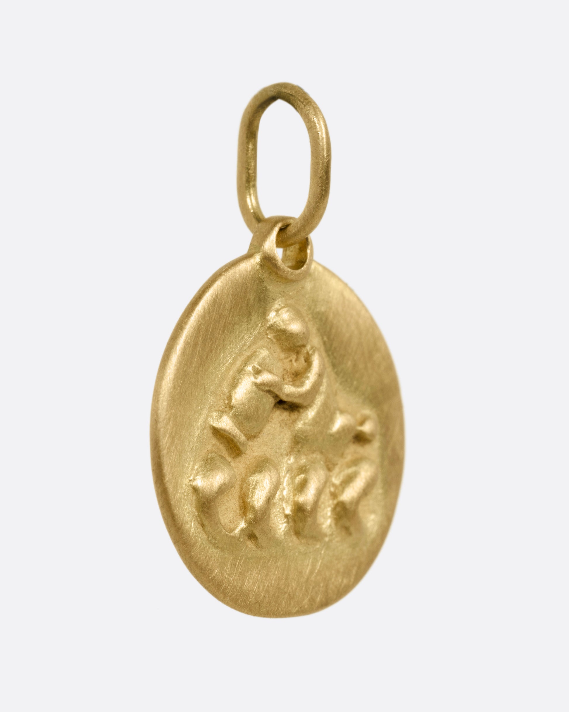 A circular yellow gold Aquarius pendant with the water bearer, shown from the side.