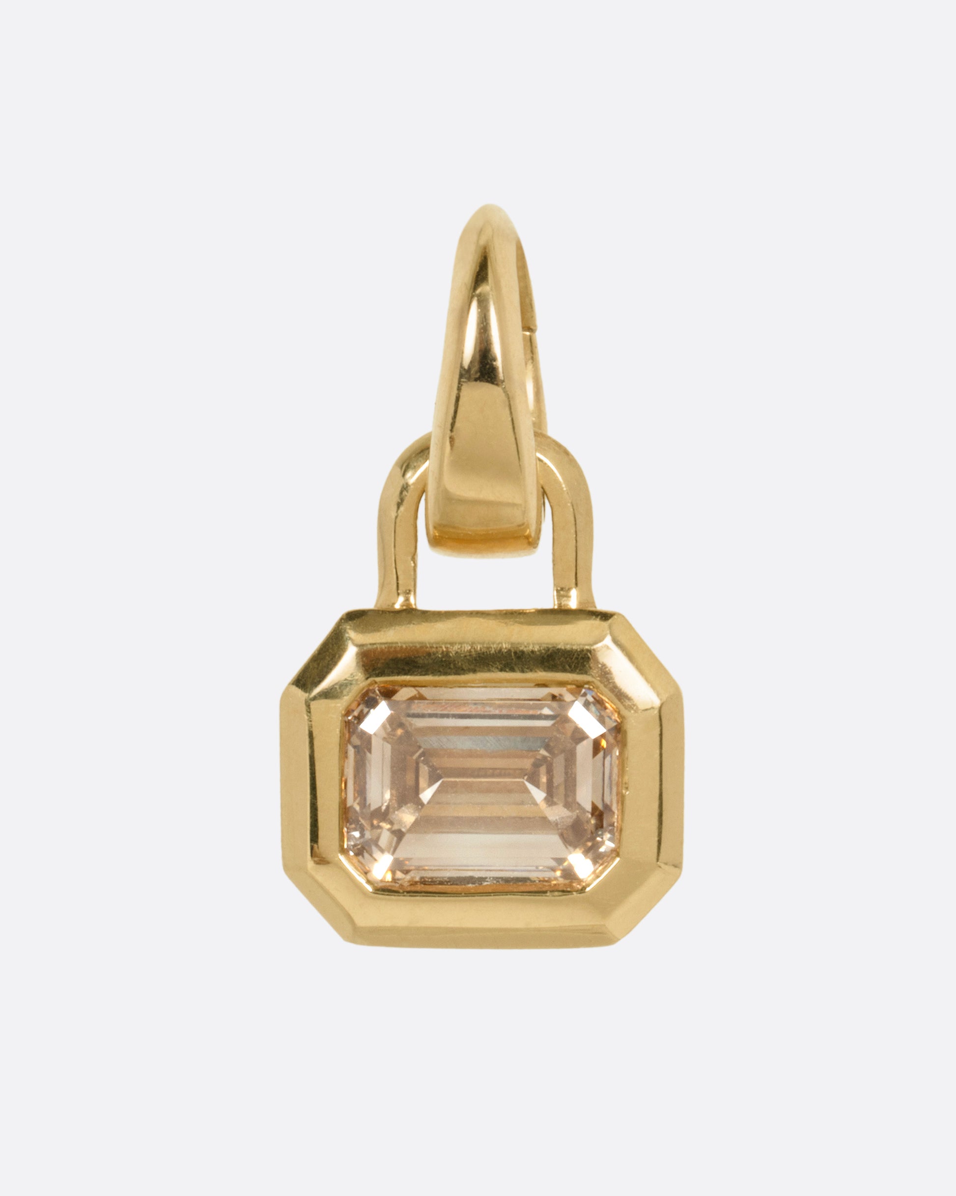 A yellow gold charm with a step cut champagne diamond, shown from the front.