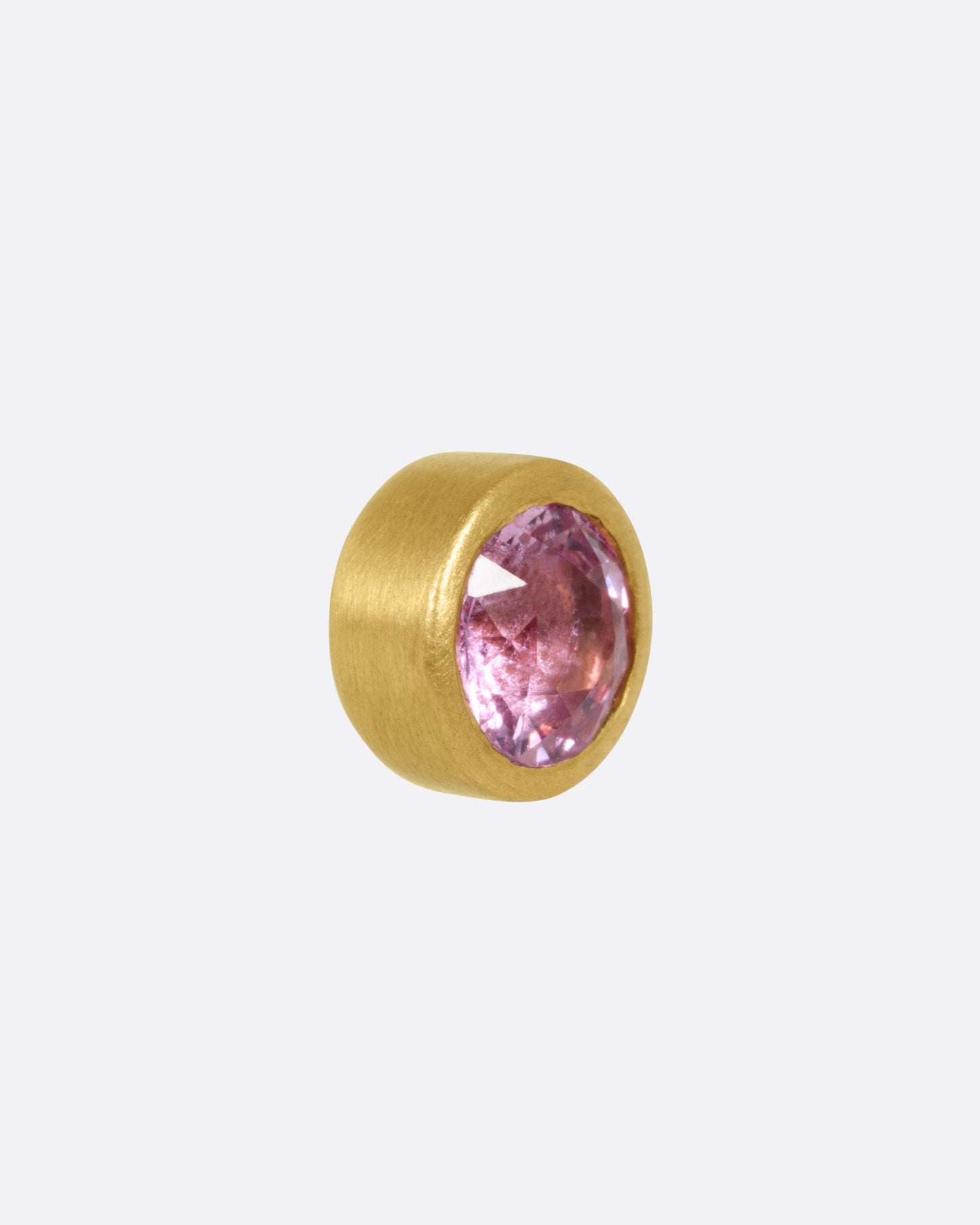 A yellow gold stud earring with a pink sapphire, shown from the side.
